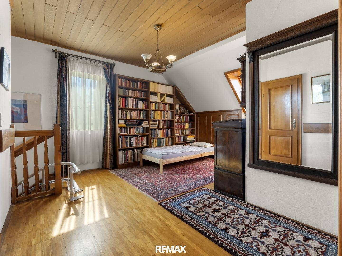 Heller Flur im Obergeschoss mit Holzdecke, Bücherregalen und einem zusätzlichen Schlafplatz.