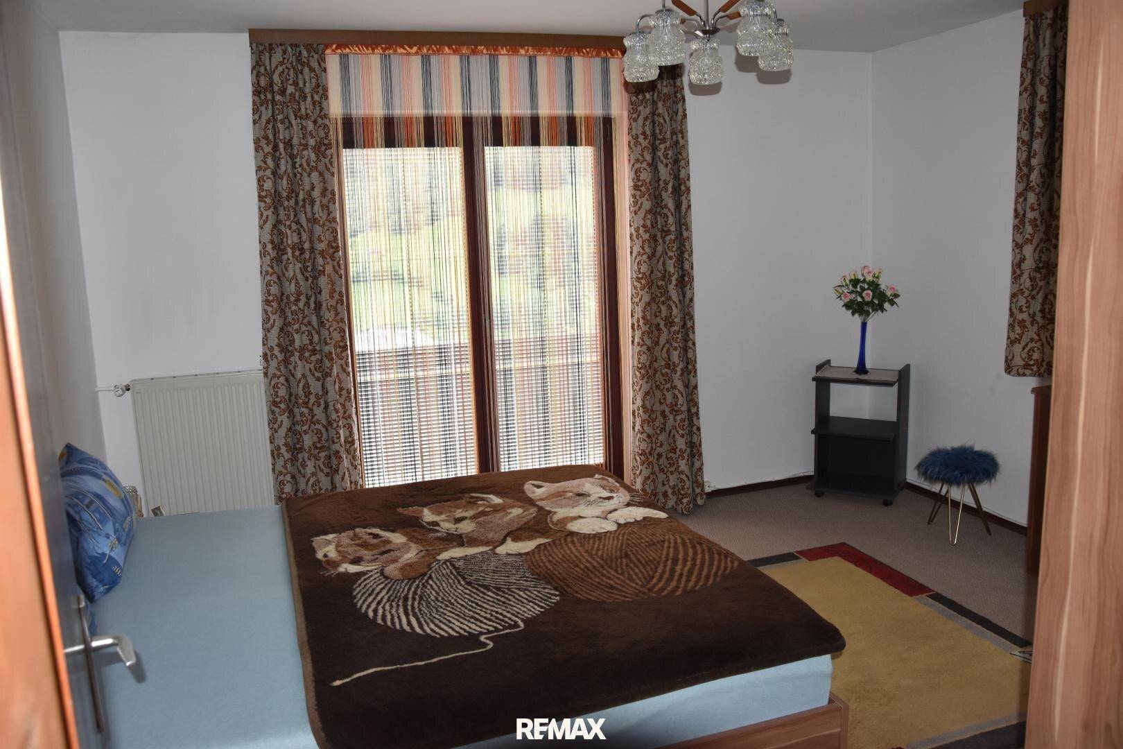Schlafzimmer mit Doppelbett, Fensterfront und Heizkörper, bietet eine angenehme Atmosphäre.