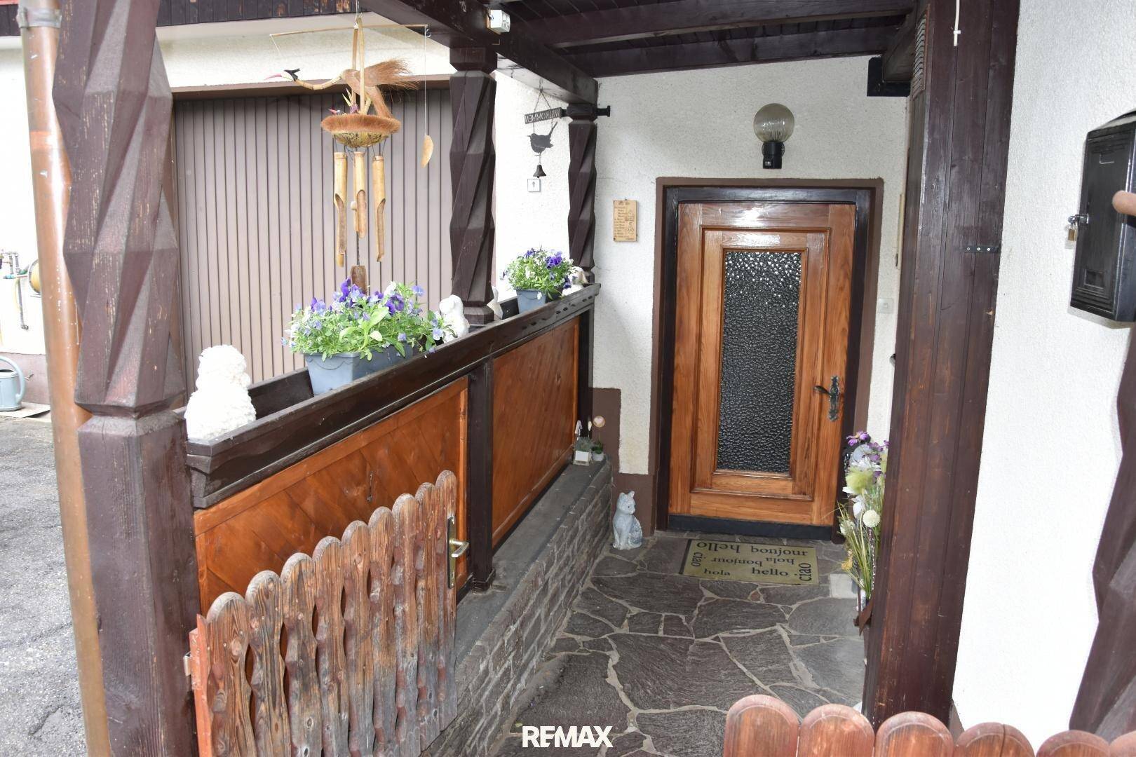 Rustikaler Eingangsbereich mit Holztür und traditionellen Holzelementen, geschmückt mit Blumen.
