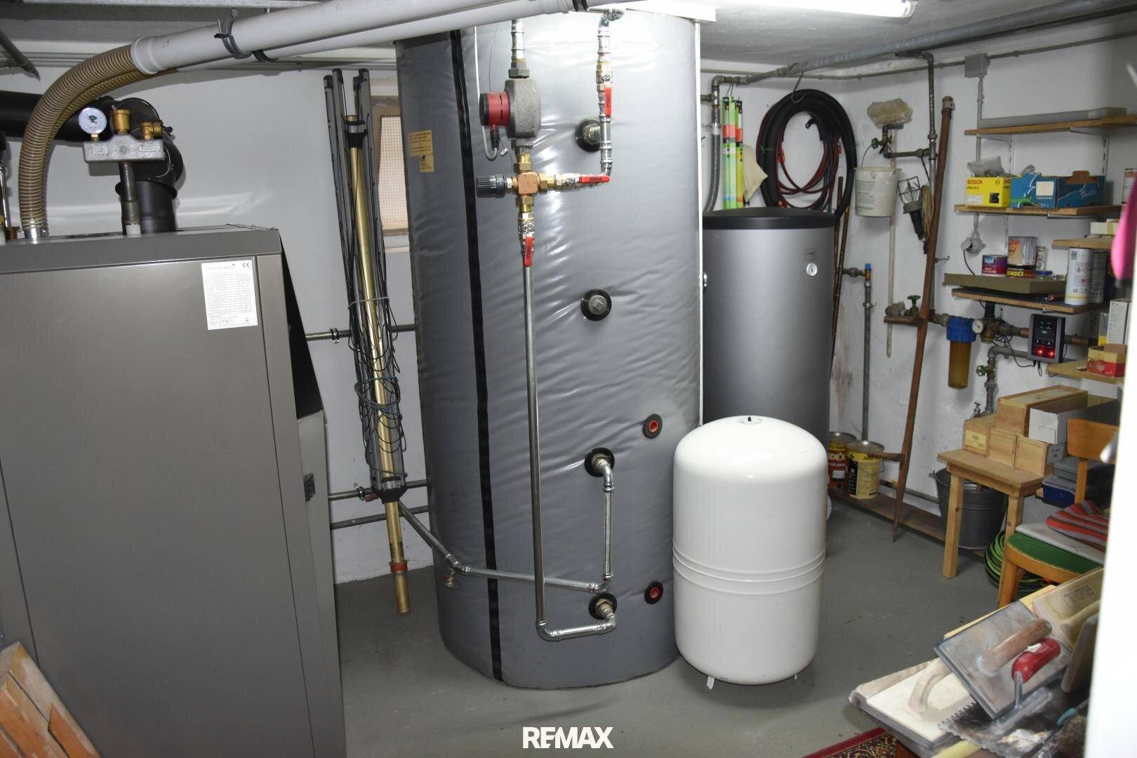 Heizungsraum im Keller mit Warmwasserspeicher und technischer Ausstattung.