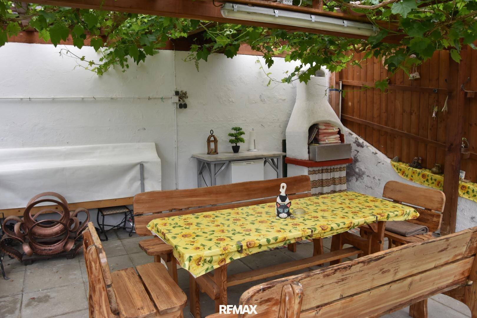 Gemütlicher Außenbereich mit Holzpergola, Esstisch und integriertem Grill für gesellige Stunden.