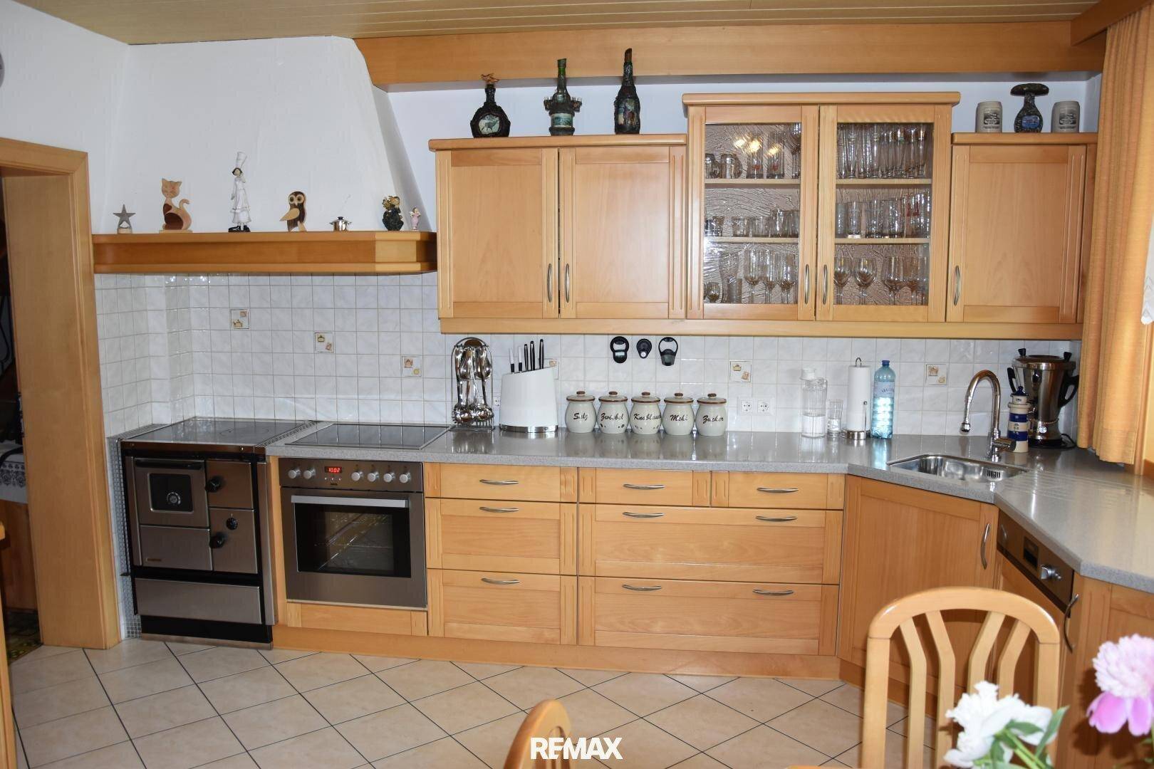 Funktionale Küche mit Holzschränken, integriertem Herd und Backofen sowie viel Arbeitsfläche.