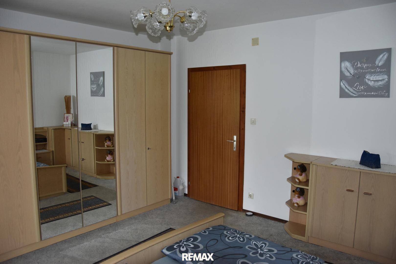 Schlafzimmer mit großem Spiegelschrank, Teppichboden und heller Wandgestaltung.