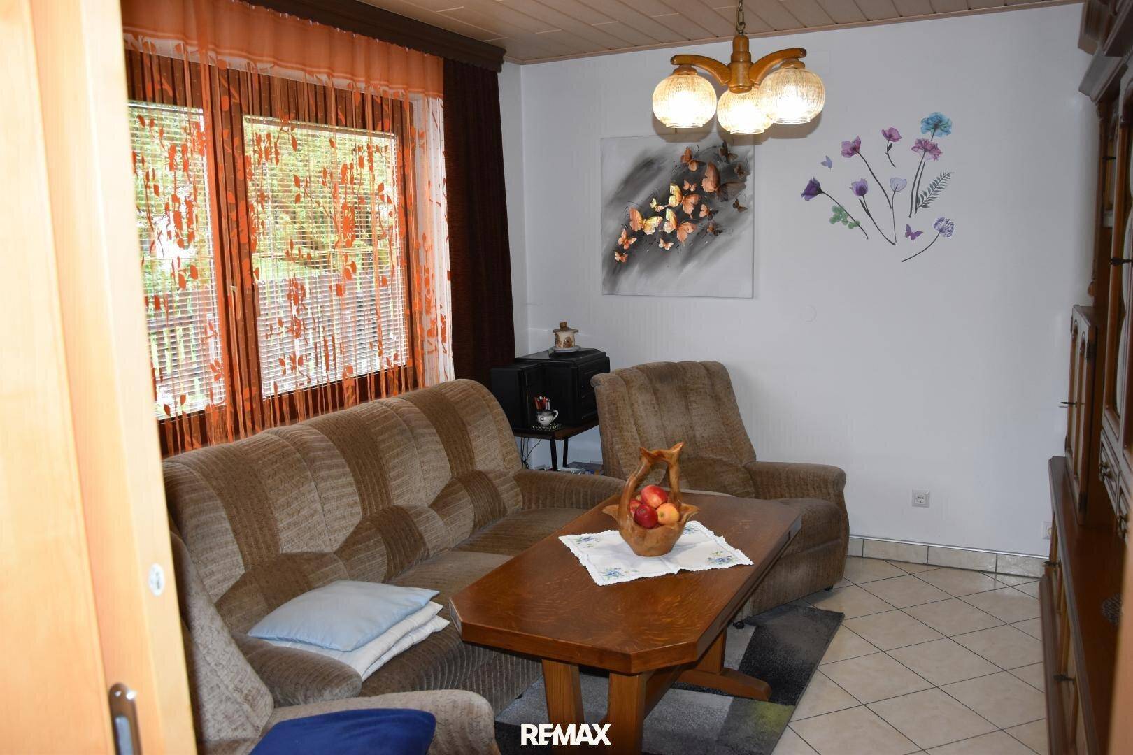 Gemütliches Wohnzimmer mit bequemen Sitzmöbeln, Holztisch und Blick nach draußen.