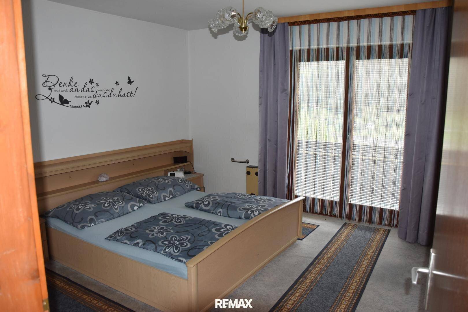 Schlafzimmer mit Doppelbett, Teppichboden und direktem Zugang zum Balkon mit schöner Aussicht.