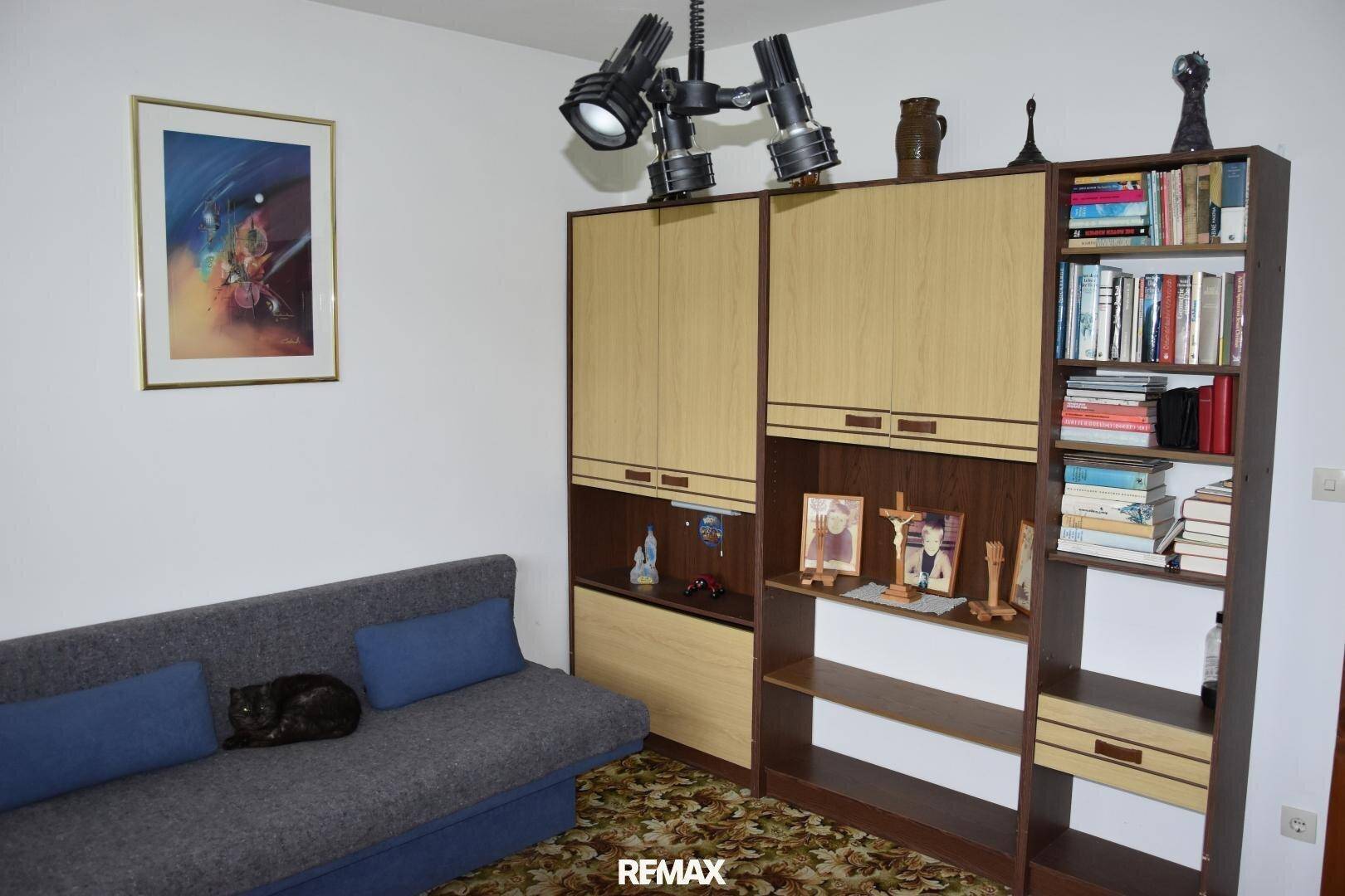 Wohnraum mit Schlafsofa, großer Schrankwand und Teppichboden, vielseitig nutzbar.