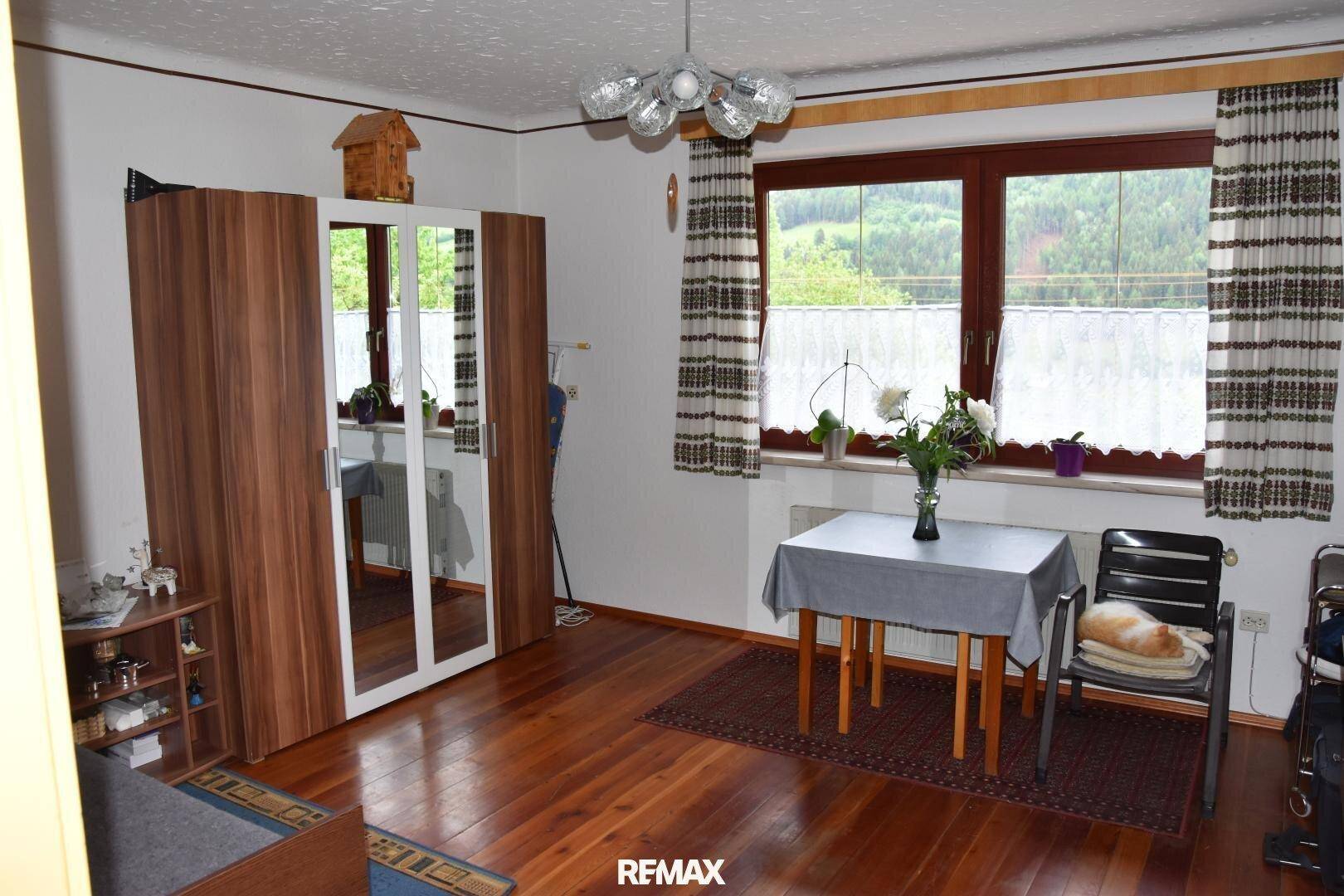 Helles Schlafzimmer mit Holzboden, großem Kleiderschrank und weitem Blick in die Natur.