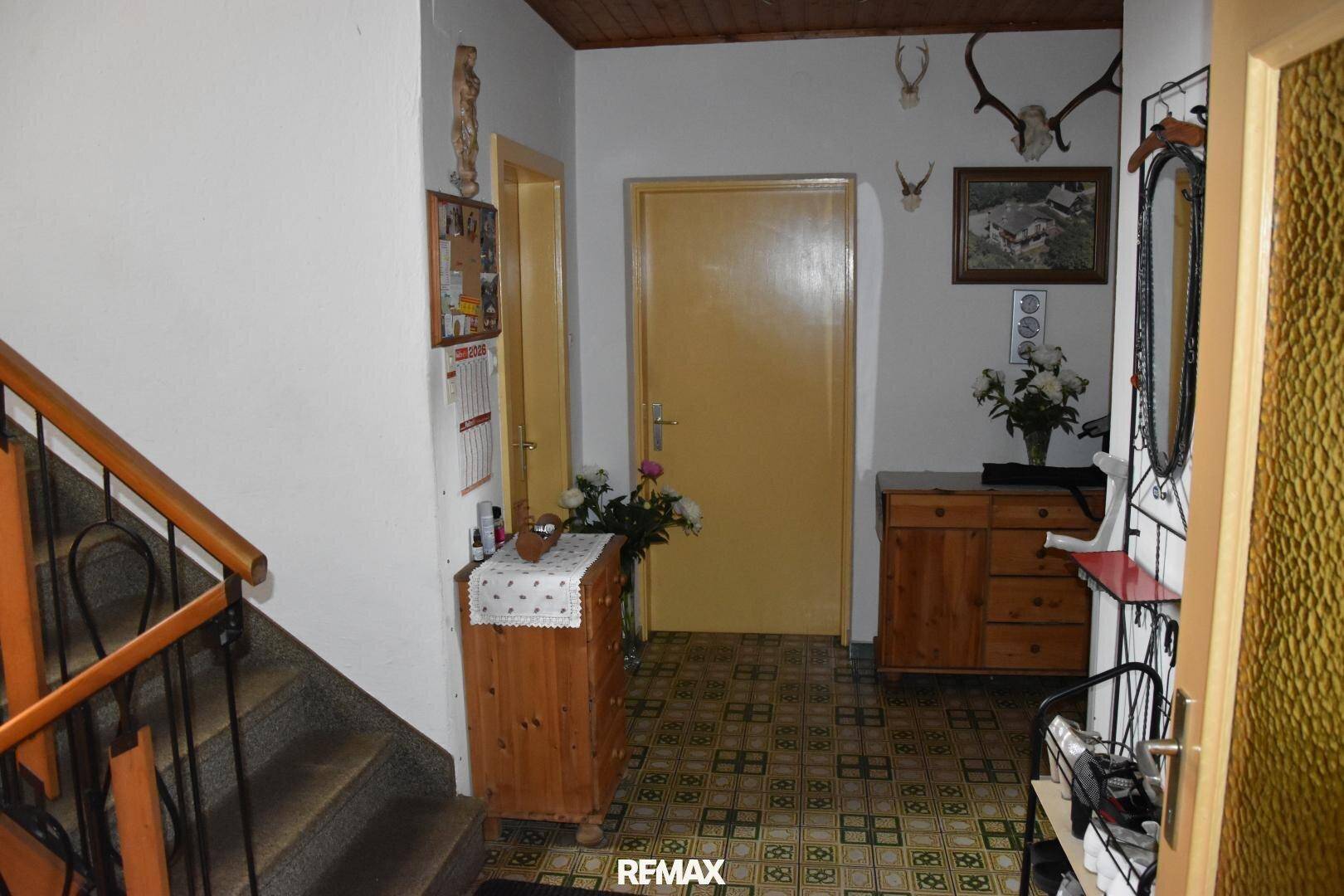 Gemütlicher Flur mit Holzmöbeln, traditionellen Hirschgeweihen und Zugang zur Treppe.