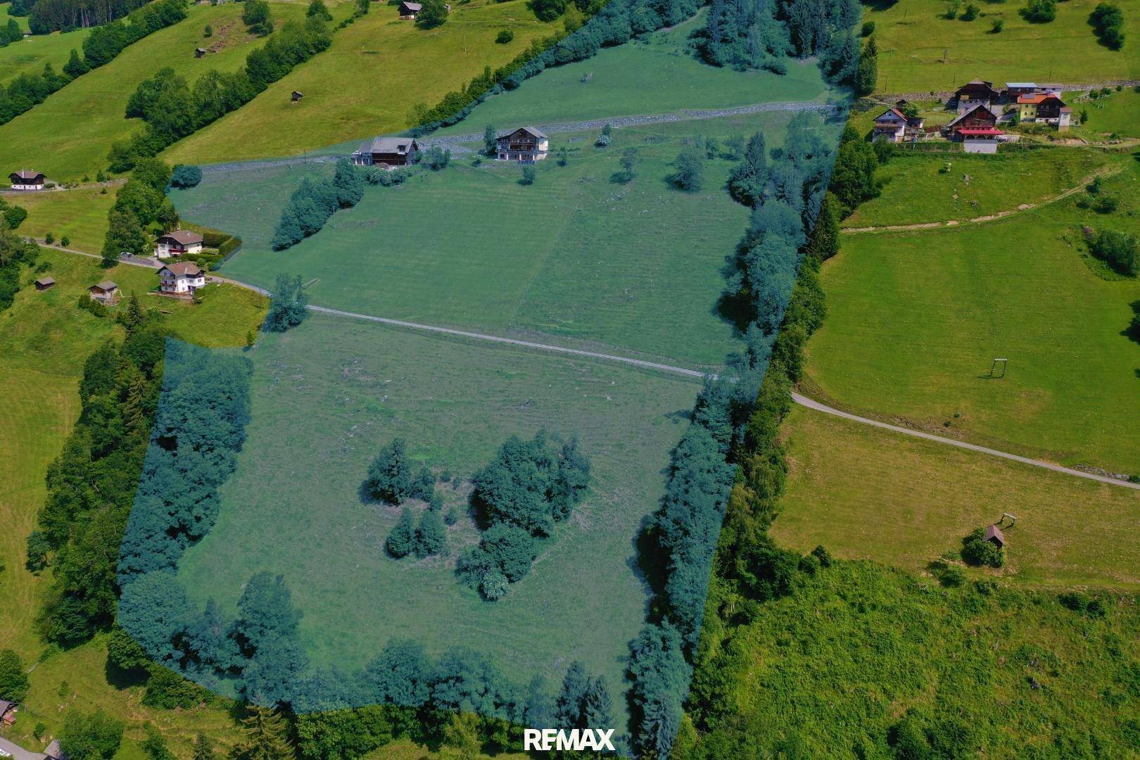 Luftaufnahme eines weitläufigen, grün umrandeten Grundstücks mit Bäumen und vereinzelten Häusern in der ländlichen Umgebung.