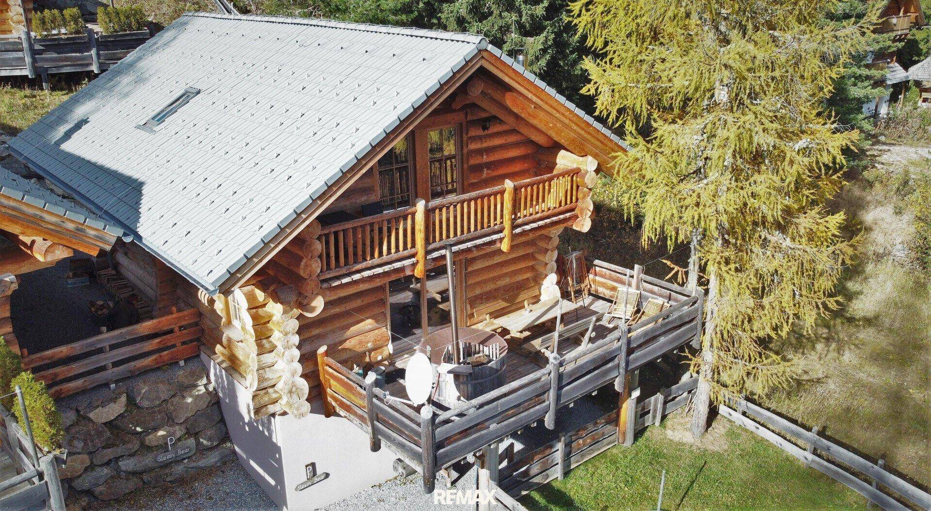 Traditionelles Blockhaus mit Holzbalkon und einer geräumigen Terrasse, eingebettet in die Berglandschaft.