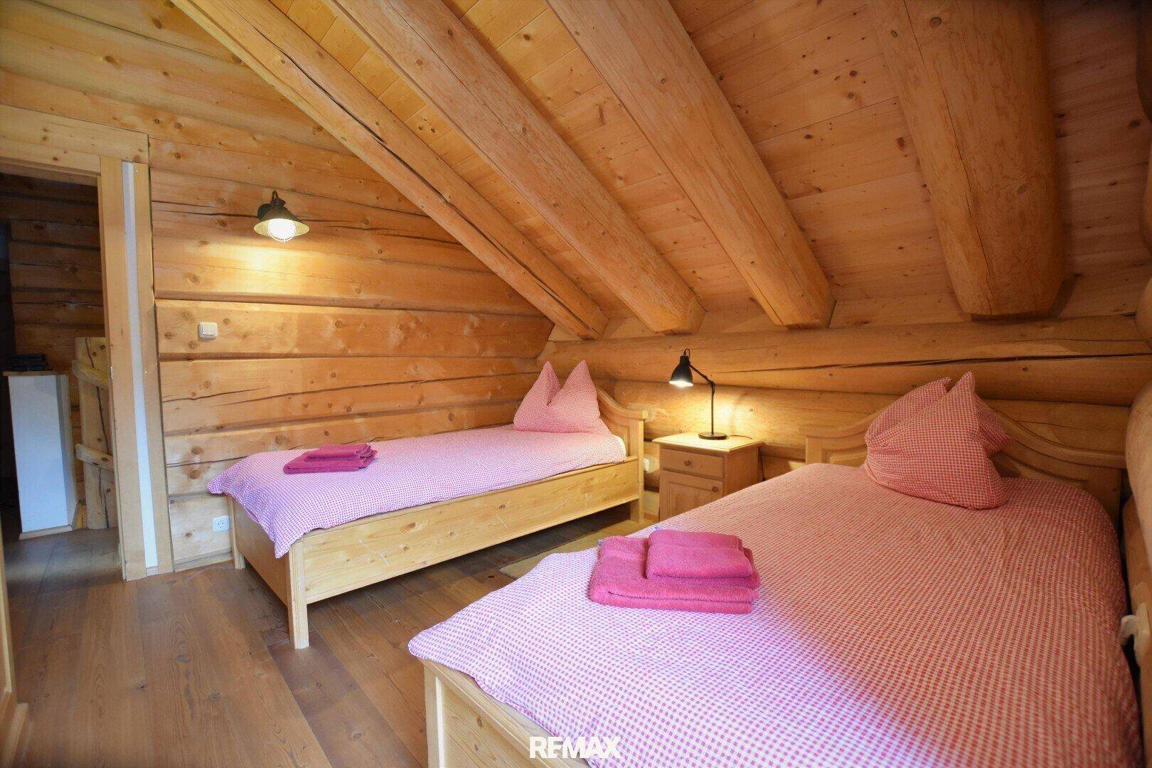 Helles Schlafzimmer mit zwei Einzelbetten, Holzbalken und Dachschrägen, ideal für Gäste.