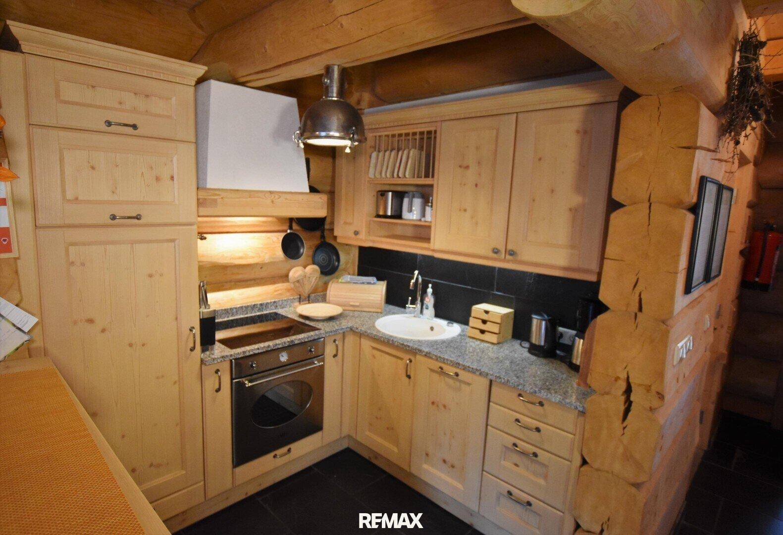 Funktionale Küche im Landhausstil mit Holzschränken, Granitarbeitsplatte und integrierten Geräten.