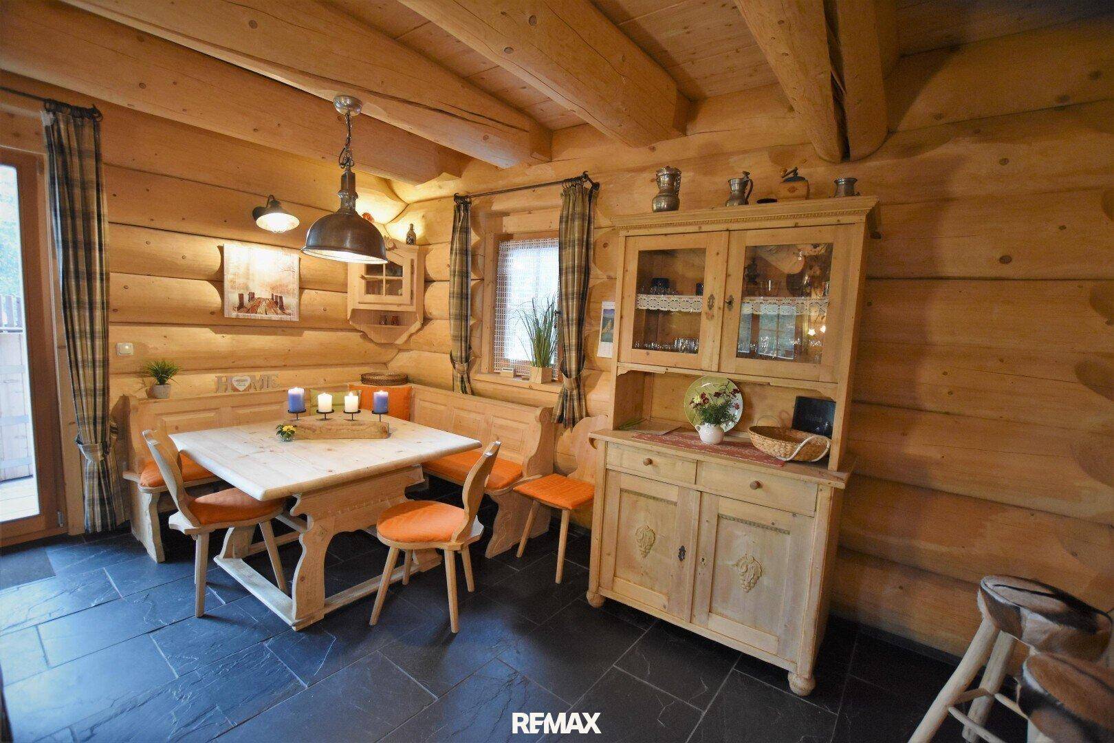 Rustikaler Essbereich mit Holztisch, Eckbank und traditionellen Möbeln im Blockhausambiente.