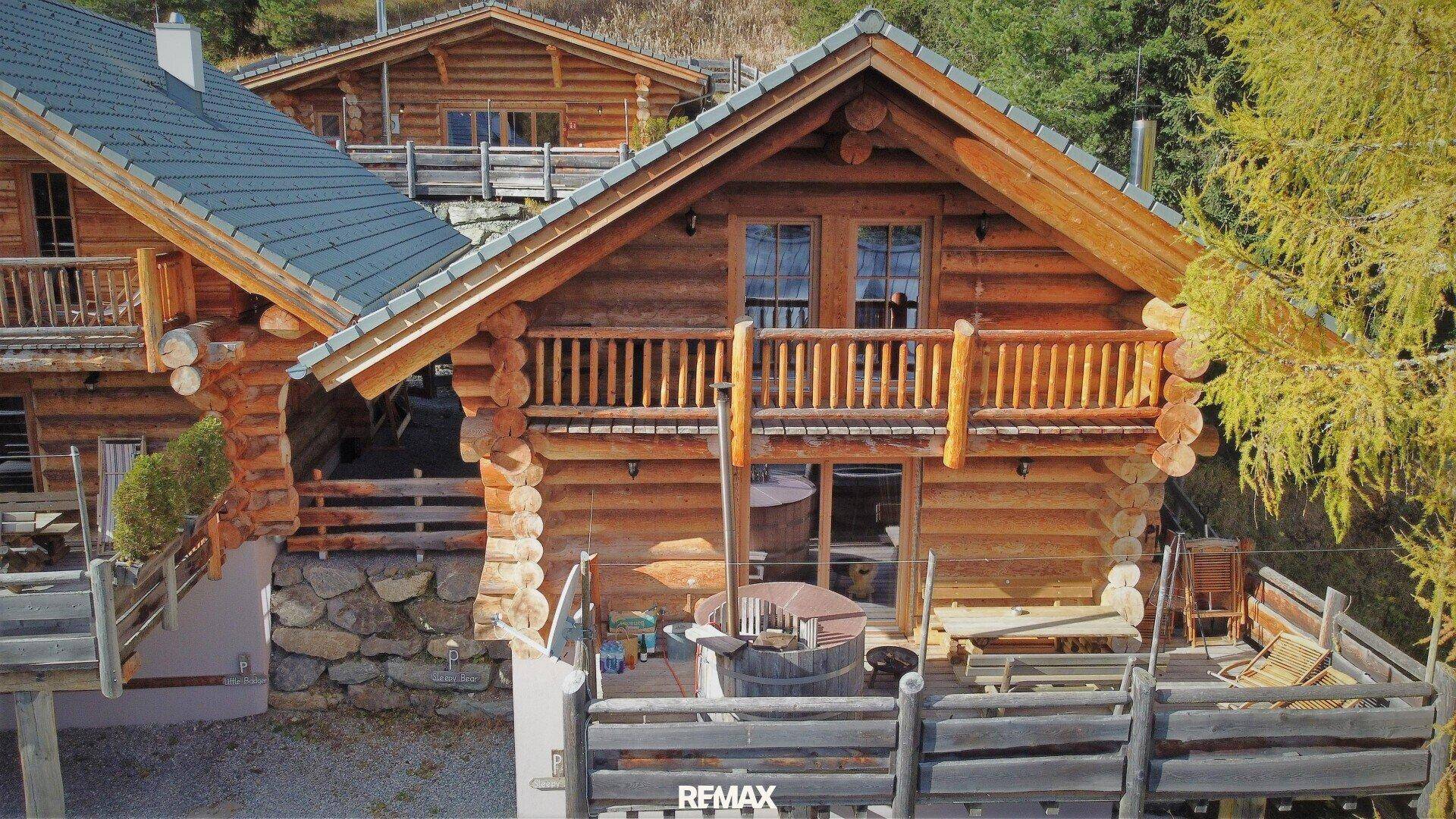Charmantes Blockhaus mit Holzfassade, Balkon und einer Terrasse mit Whirlpool im Freien.
