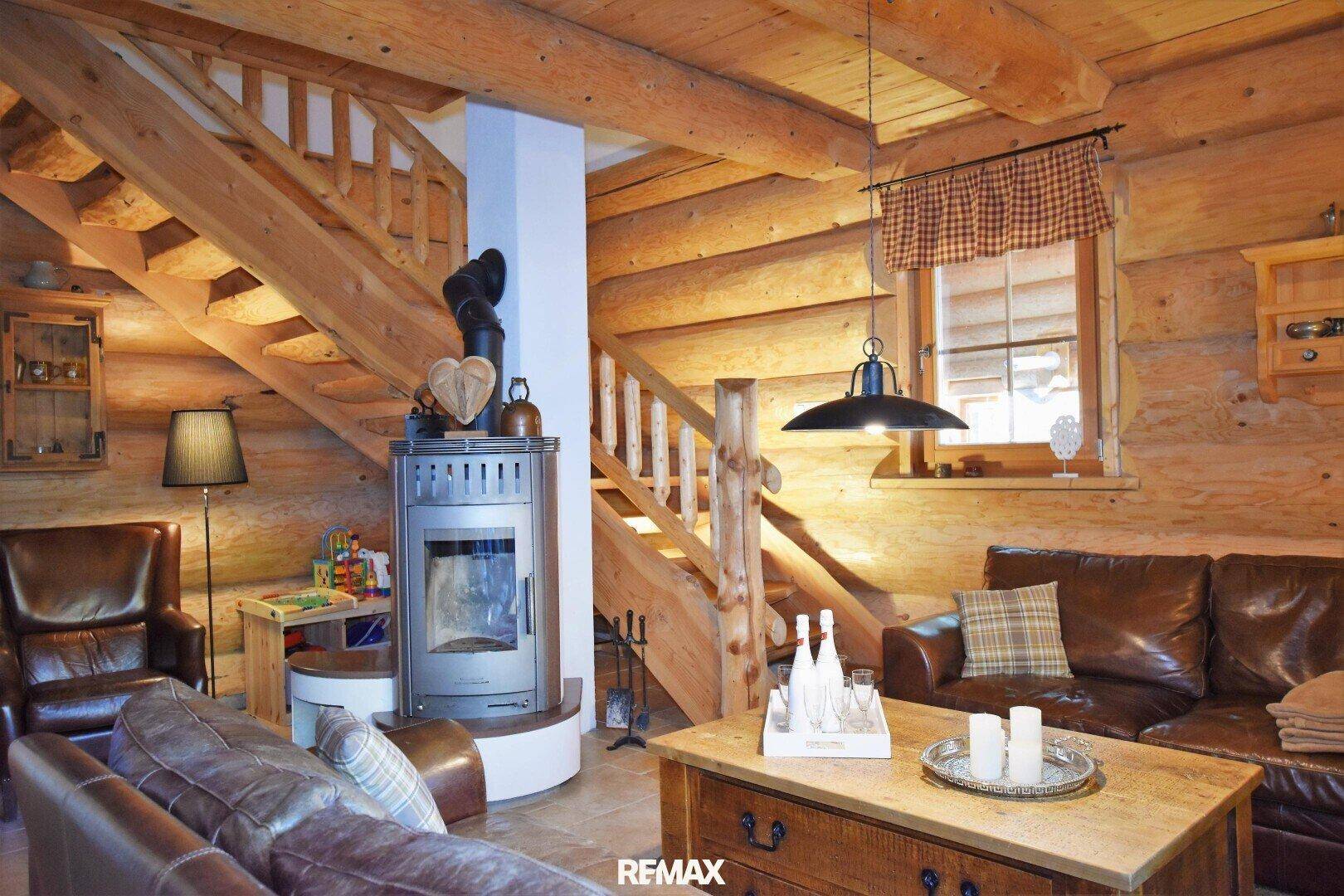 Gemütliches Wohnzimmer im Chalet-Stil mit Holzbalken, Kaminofen und Ledersofas.