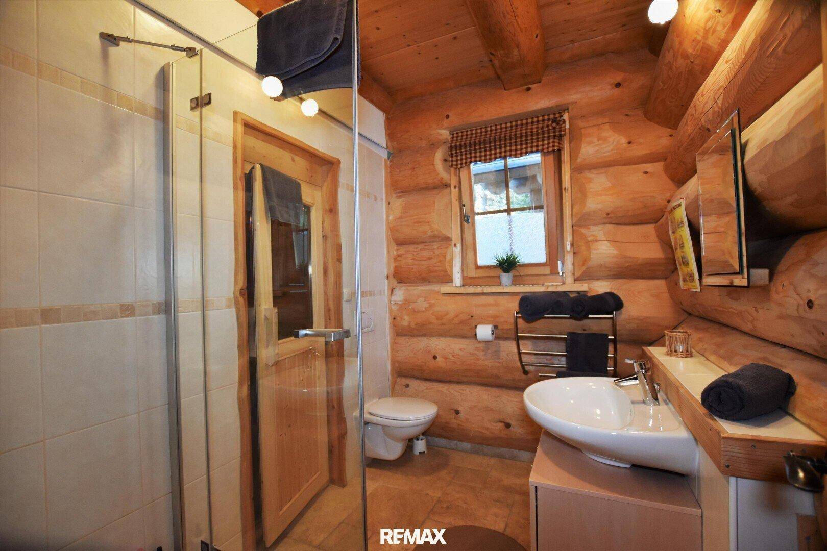 Modernes Badezimmer mit Duschkabine, Einzelwaschbecken und Holzwänden im Chalet-Stil.