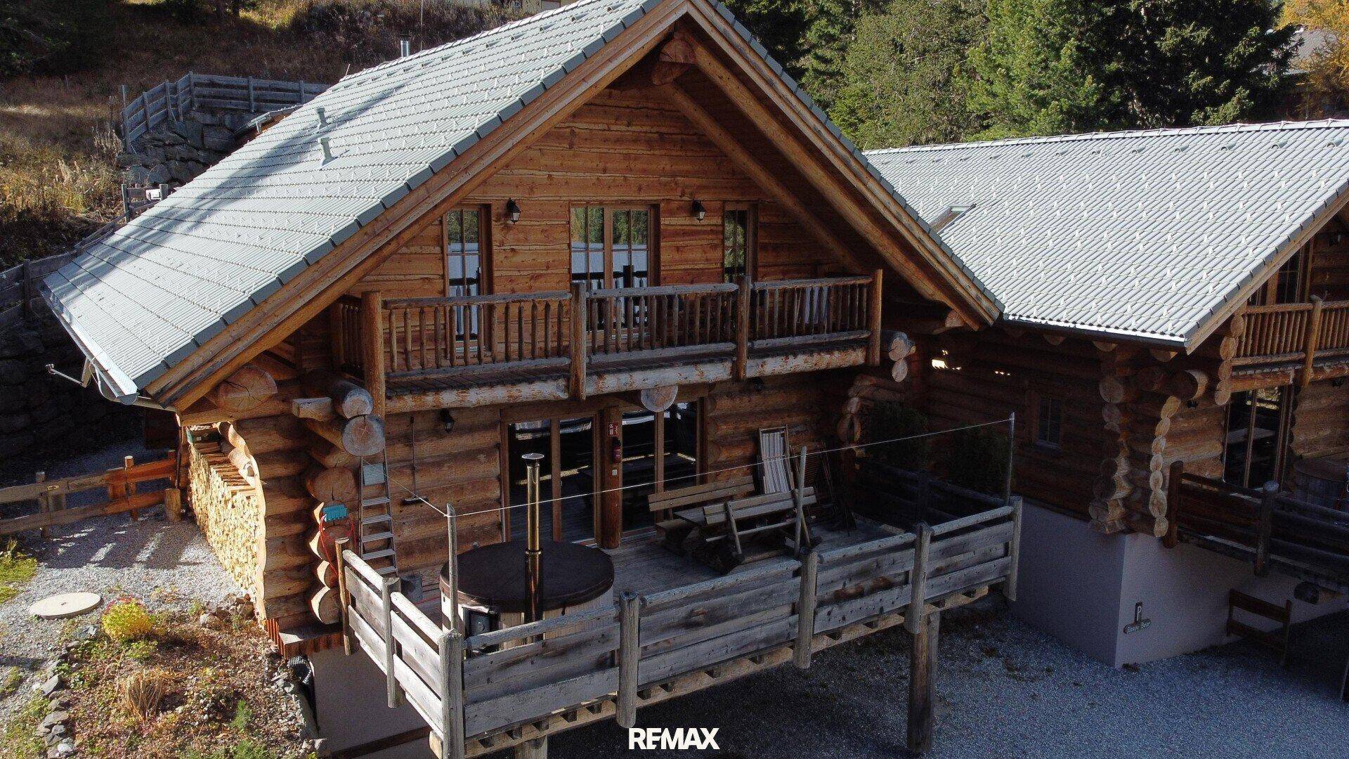 Charmantes Holzchalet mit einer großen Holzterrasse und Balkon, umgeben von alpiner Natur.