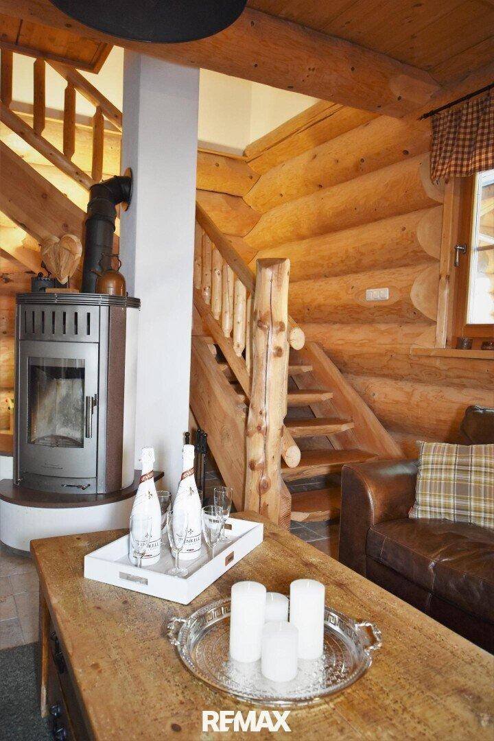 Detailansicht des Wohnzimmers mit Kaminofen, Holztreppe und rustikalen Möbeln.
