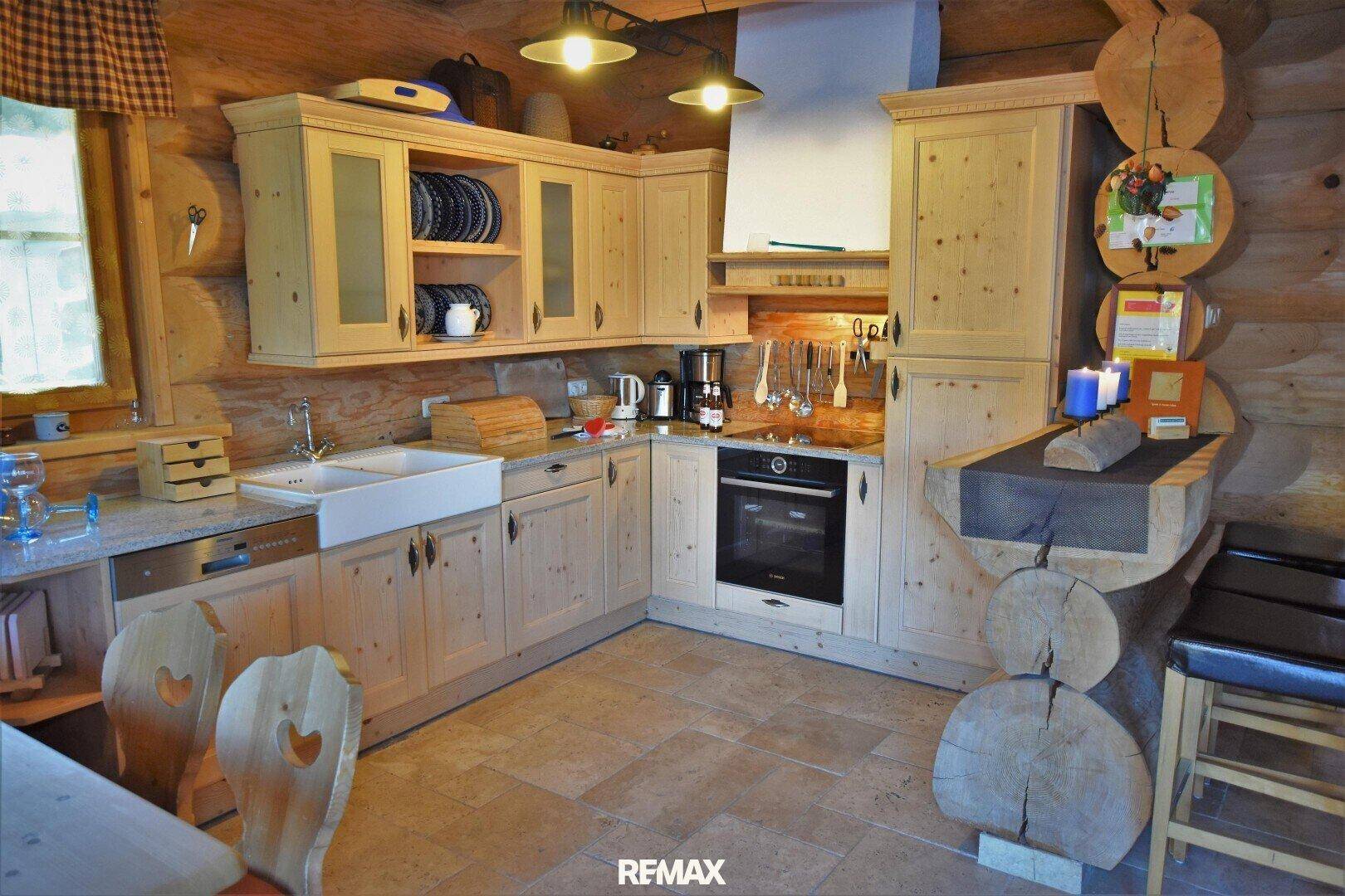 Traditionelle Holzküche mit Einbauschränken, Keramikspüle und gefliestem Boden im Landhausstil.