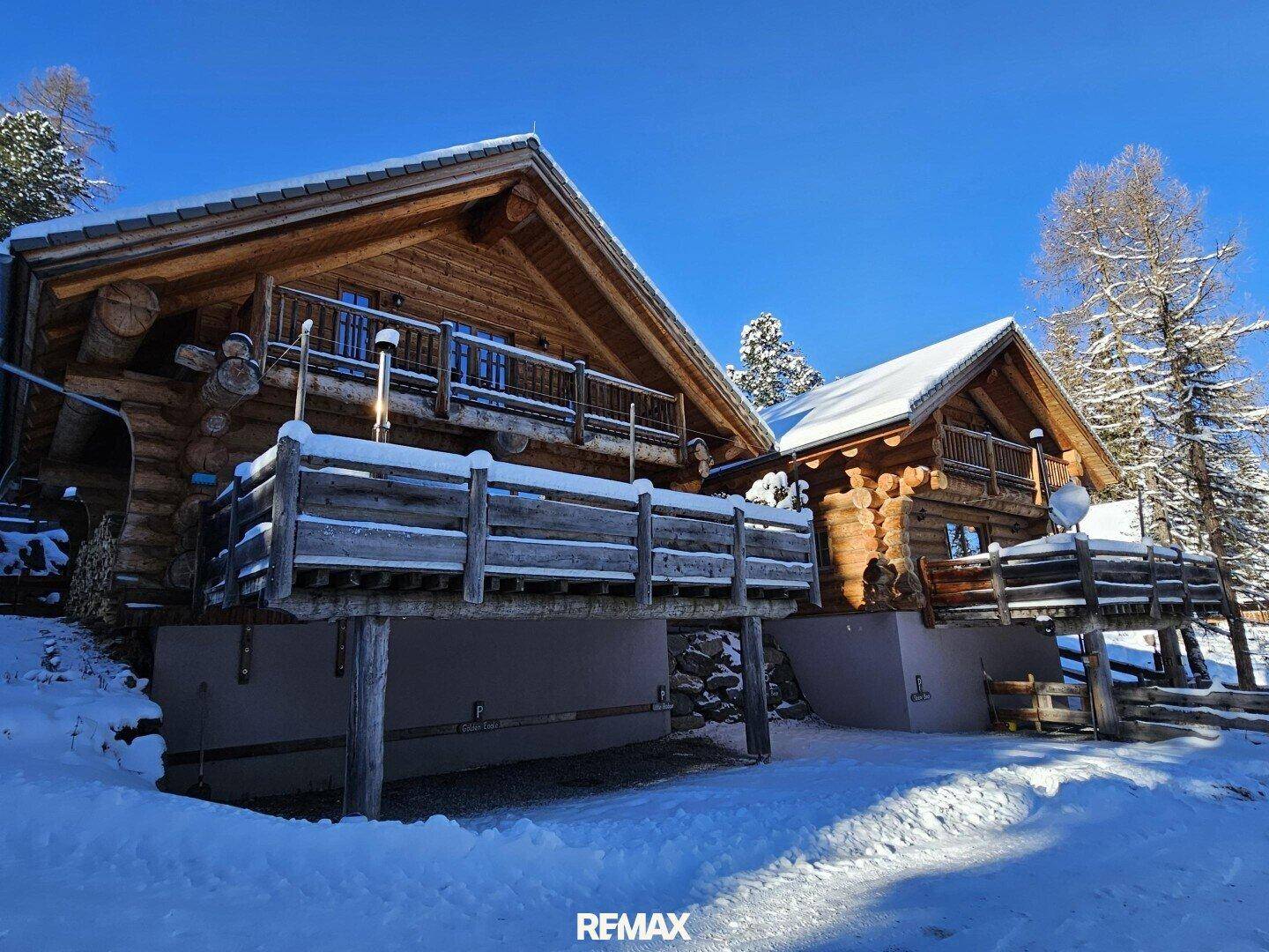 Die Holzchalets im Winter mit tiefem Schnee und klarem blauen Himmel.