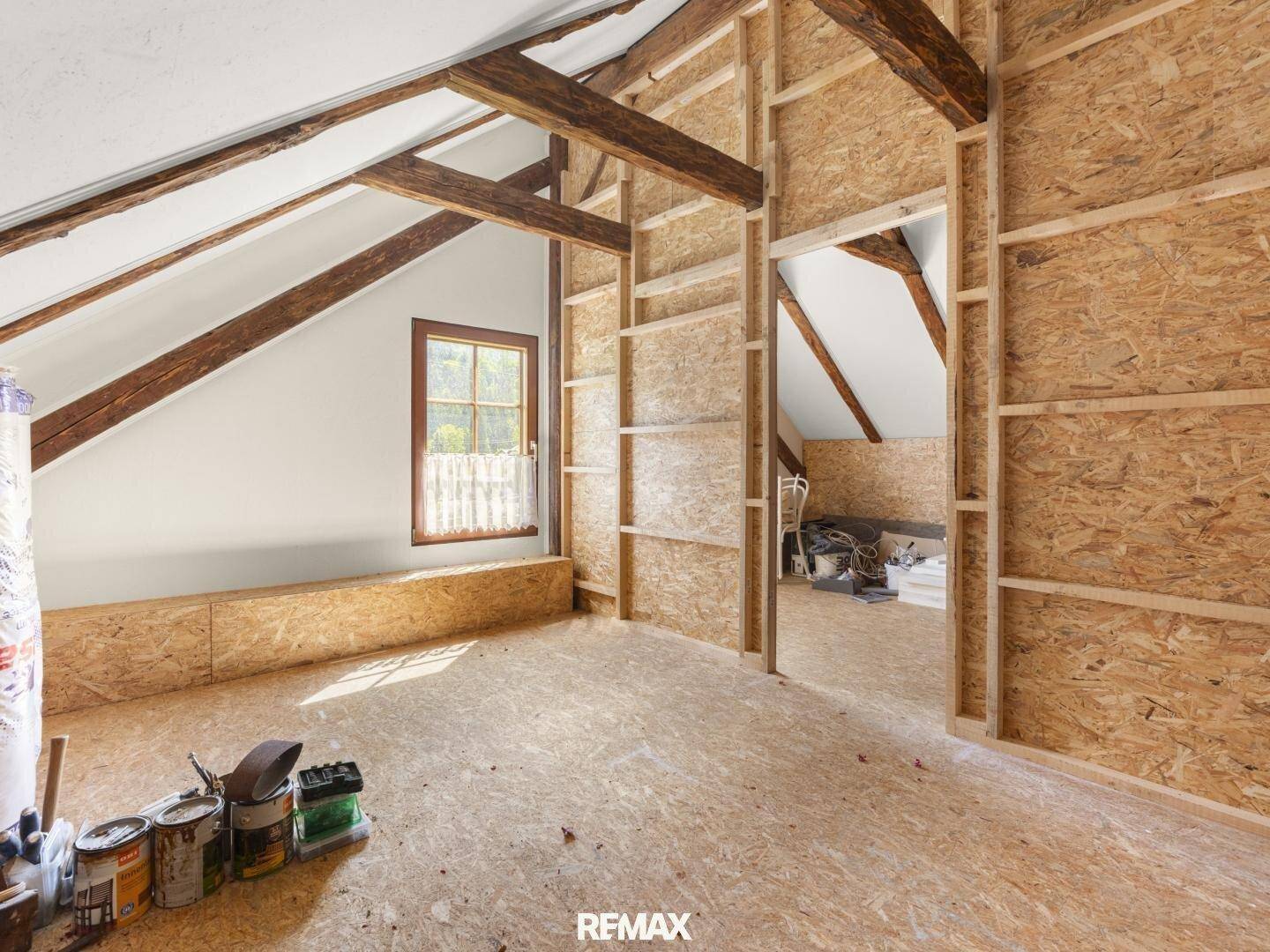 Unausgebauter Dachboden mit sichtbaren Holzbalken und OSB-Platten, bereit für den Ausbau.
