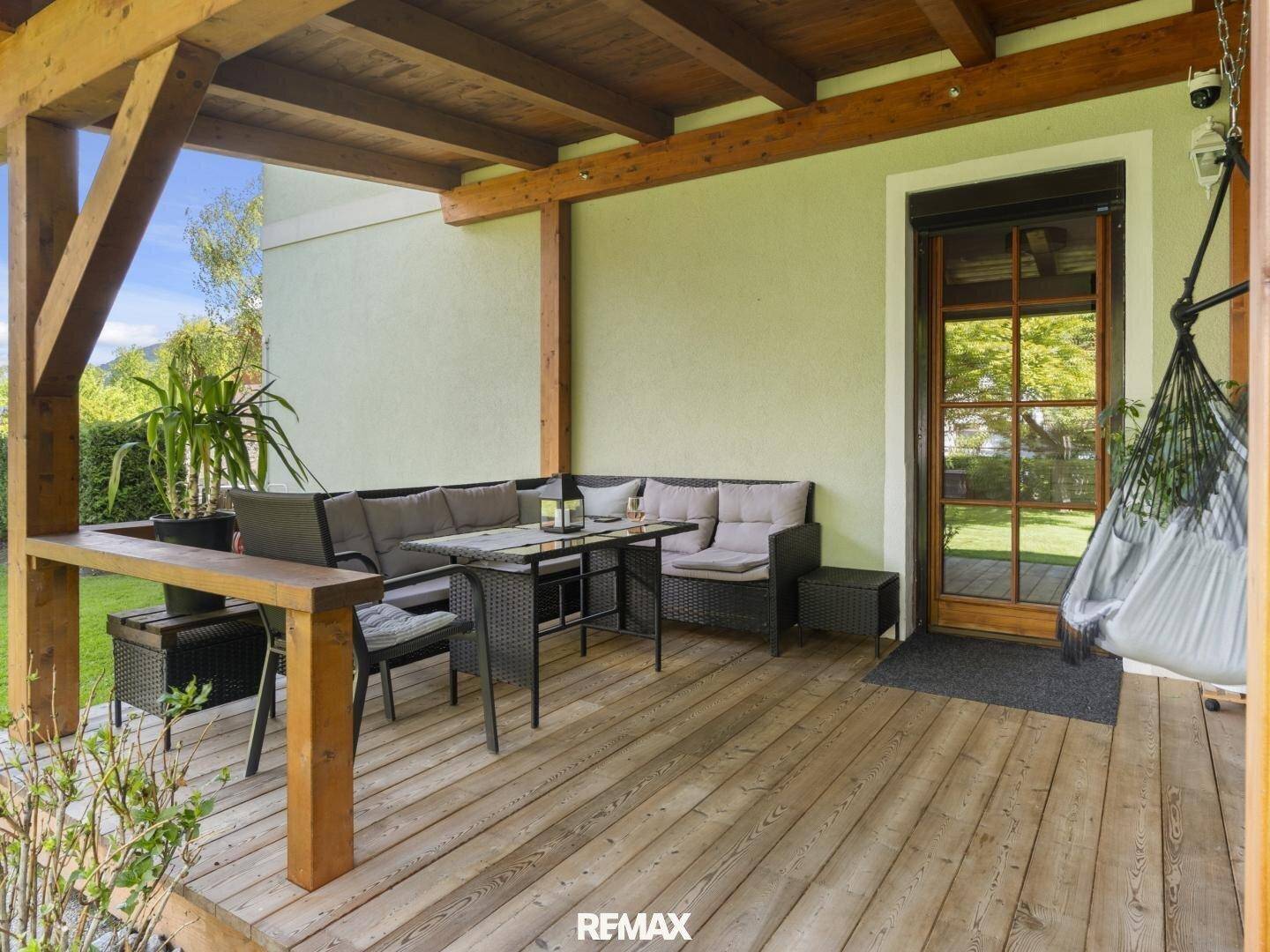 Überdachte Holzterrasse mit bequemen Loungemöbeln, ideal für entspannte Stunden im Freien.