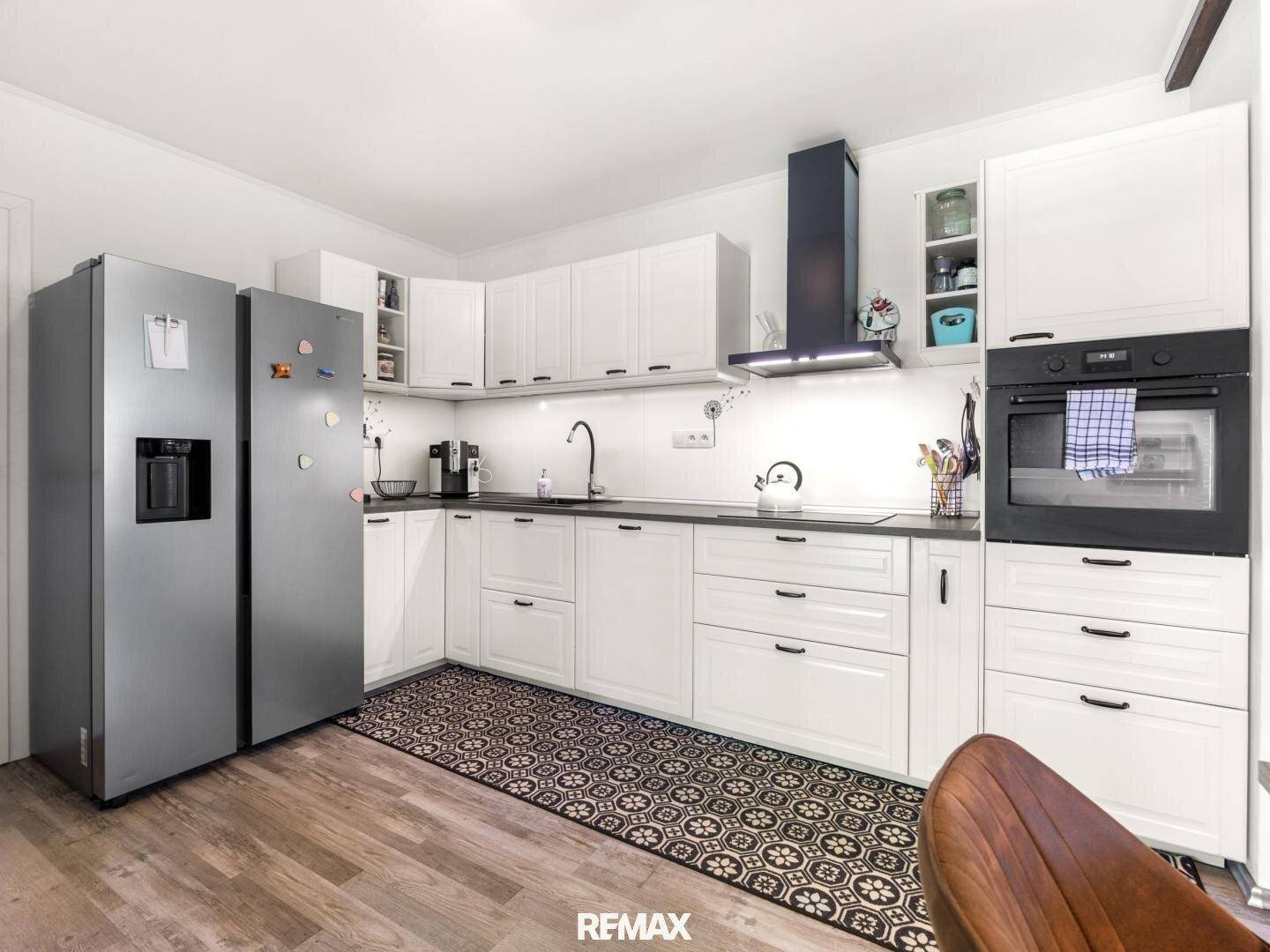 Funktionale Küche mit weißen Schränken, modernen Geräten und einem großen Side-by-Side-Kühlschrank.
