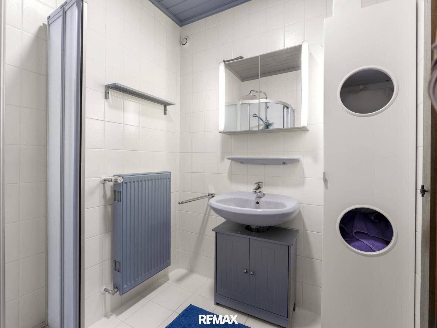 Modernes Badezimmer mit Dusche, Waschbecken und Spiegelschrank in hellen Farben.
