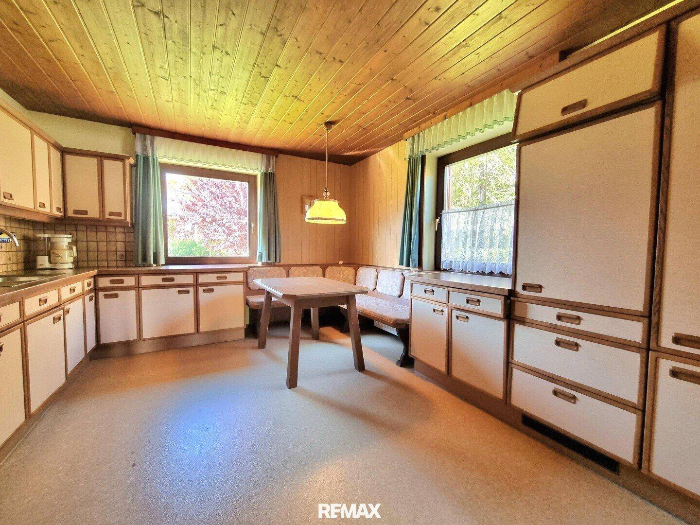 Gemütliche Küche im Landhausstil mit Holztäfelung und Essecke.