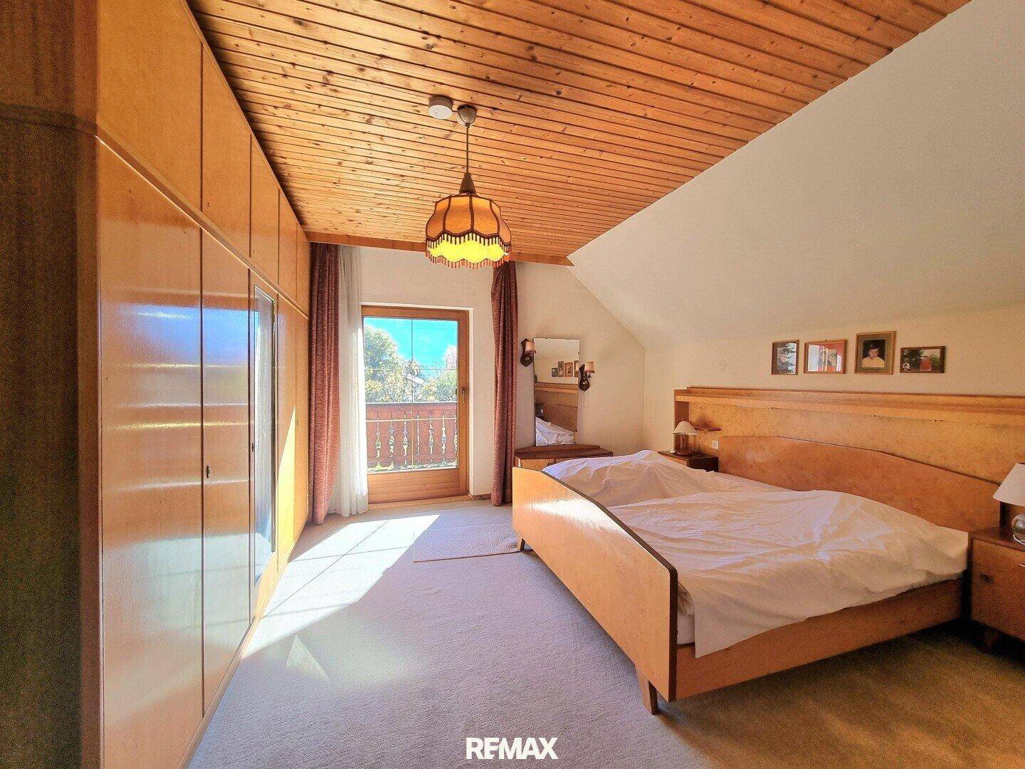 Schlafzimmer im Dachgeschoss mit Doppelbett, Einbauschränken und Balkonzugang.