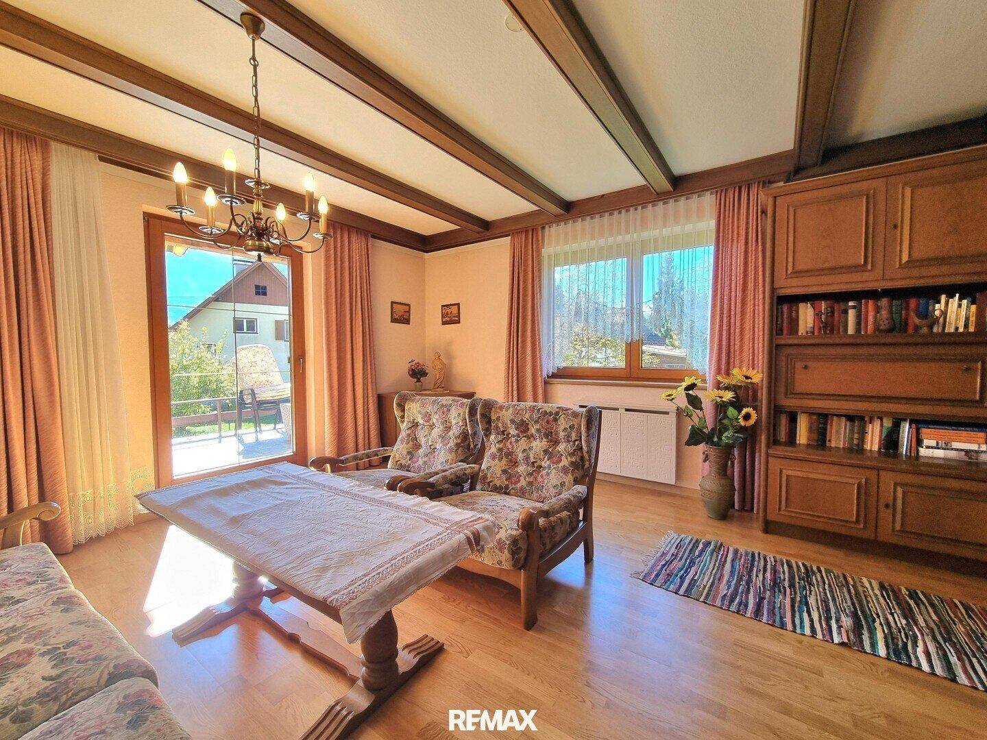 Rustikales Wohnzimmer mit Holzbalkendecke, traditionellen Möbeln und Zugang zur Terrasse.