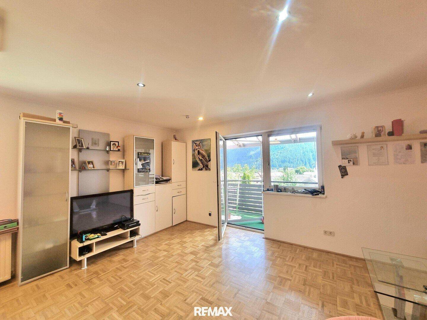 Wohnzimmer mit Parkettboden, TV-Möbeln und Zugang zu einem Balkon mit Bergblick.