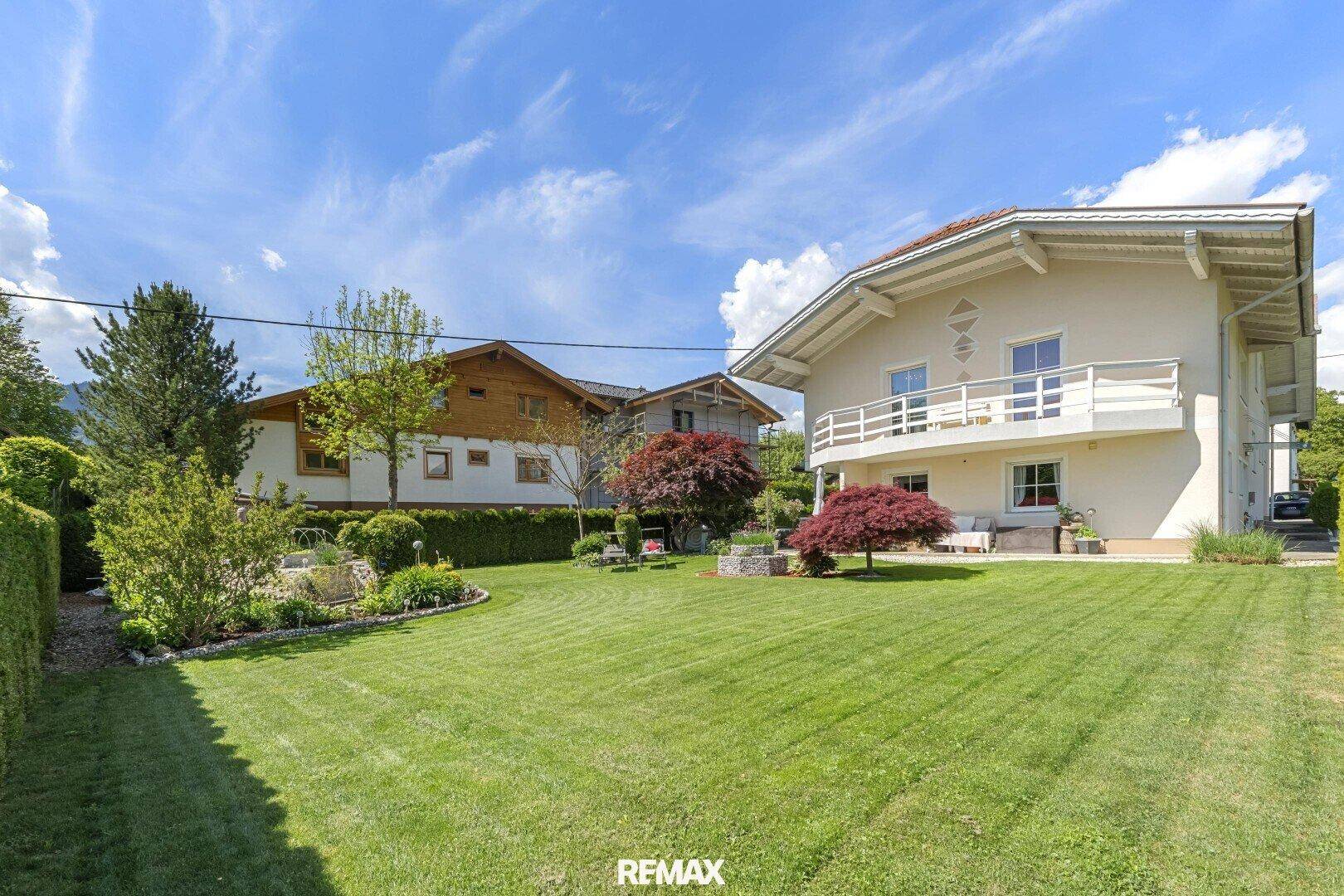 Weitläufiger Garten mit gepflegtem Rasen und hoher Hecke, umgeben von ländlicher Idylle.