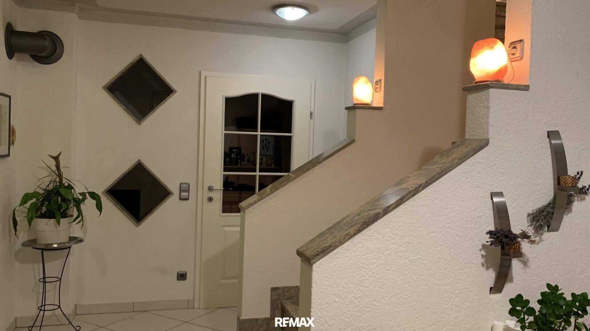 Eingangsbereich mit heller Tür, dekorativen Wandleuchten und Zugang zum Treppenhaus.