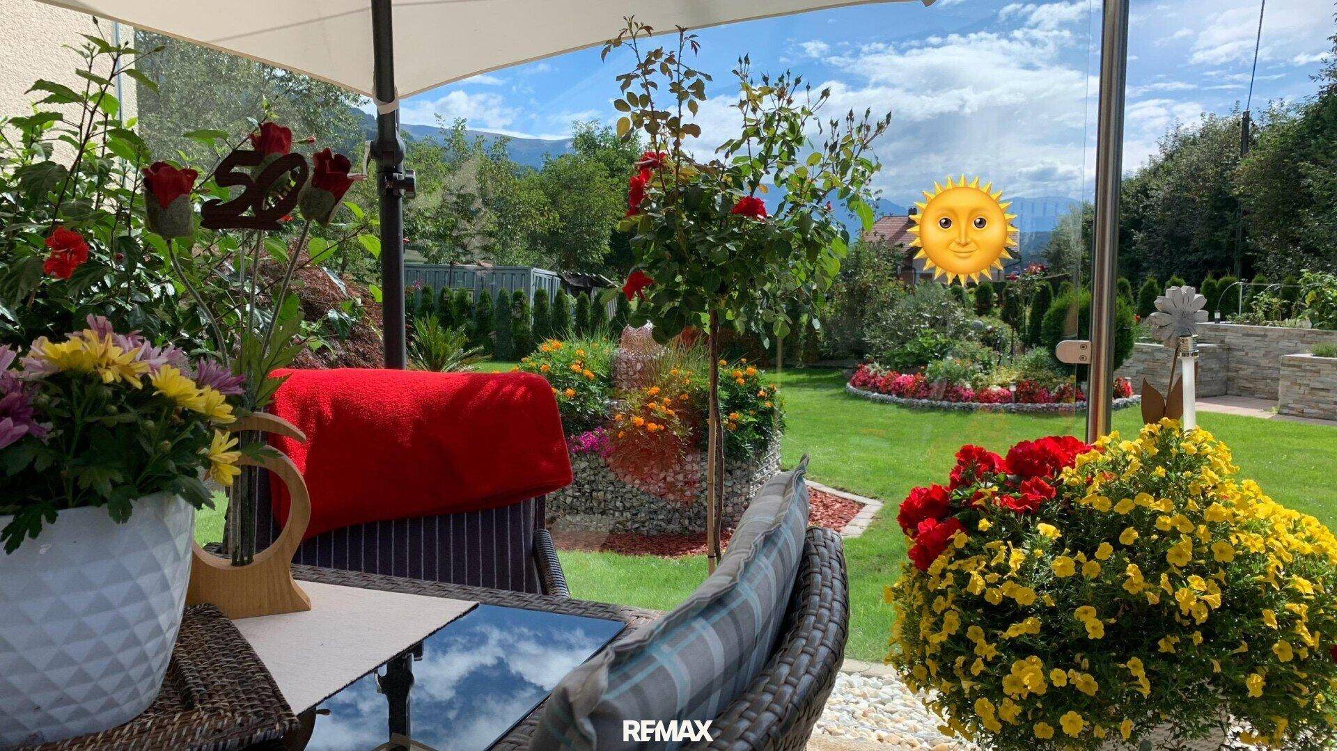 Sonnige Terrasse mit bequemen Sitzgelegenheiten und üppigen Blumenarrangements, ideal zum Entspannen.
