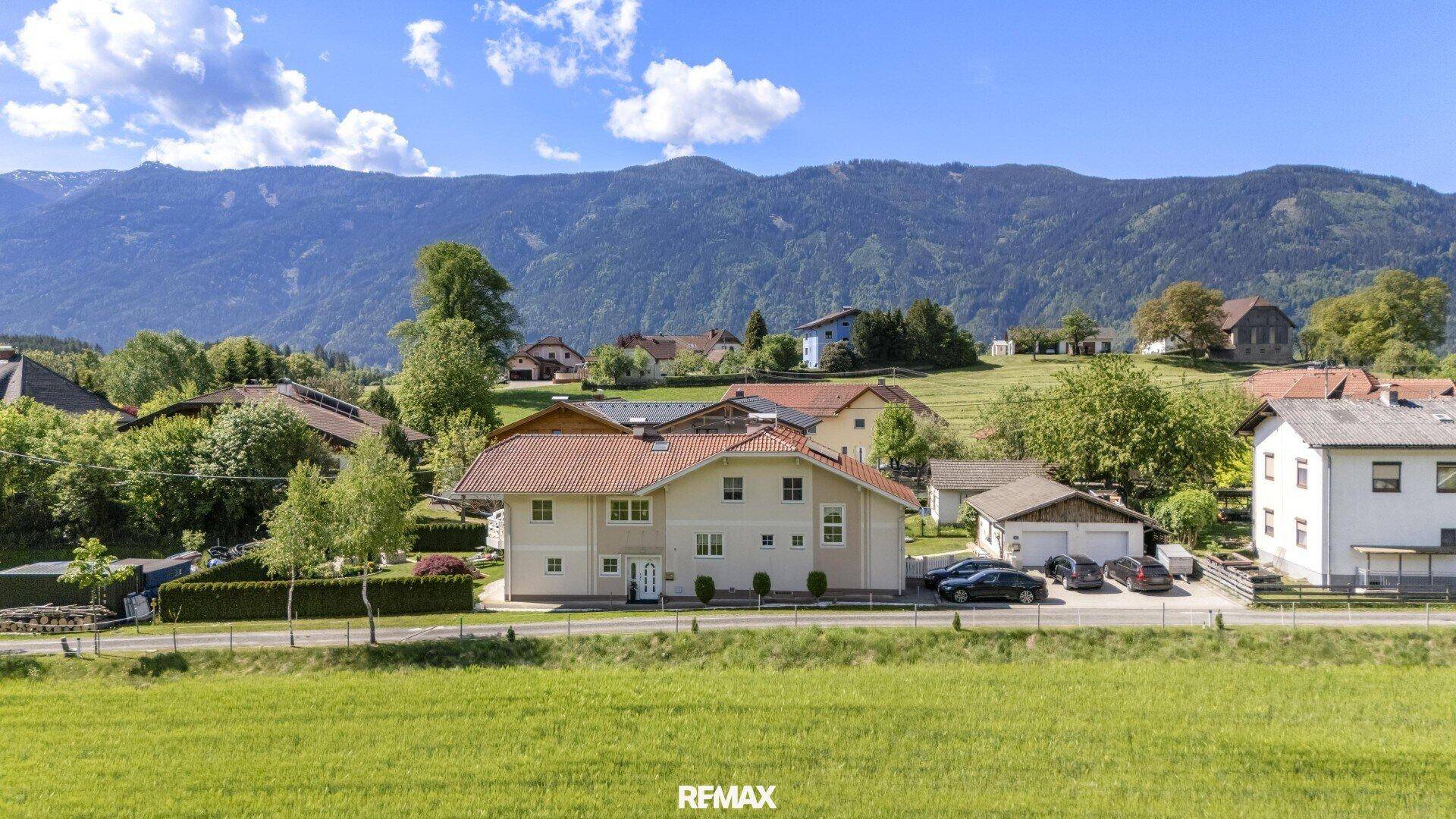 Ansicht des Hauses mit rotem Ziegeldach und gepflegter Fassade vor einer malerischen Bergkulisse.