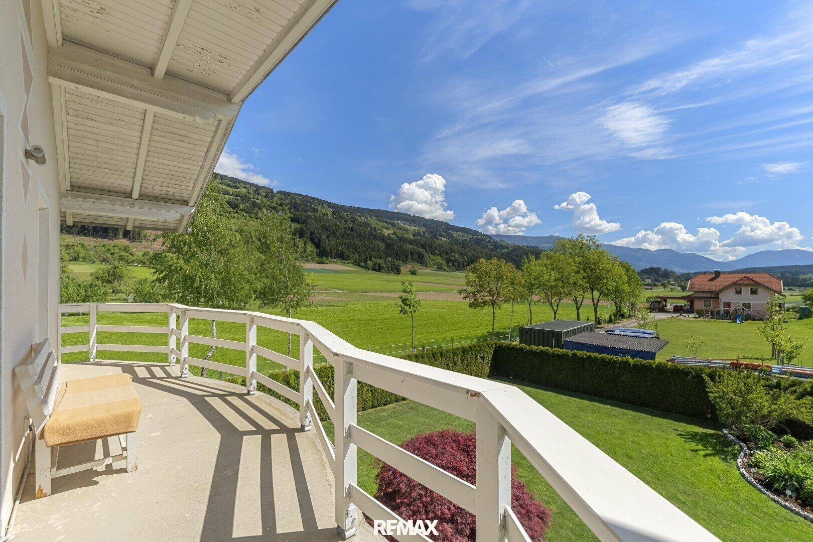 Geräumiger Balkon mit weißem Geländer und einem weiten, grünen Blick auf die umliegende Landschaft.