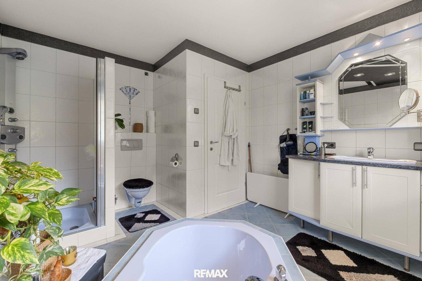 Geräumiges Badezimmer mit Eckbadewanne, Dusche, Doppelwaschbecken und hellen Fliesen.