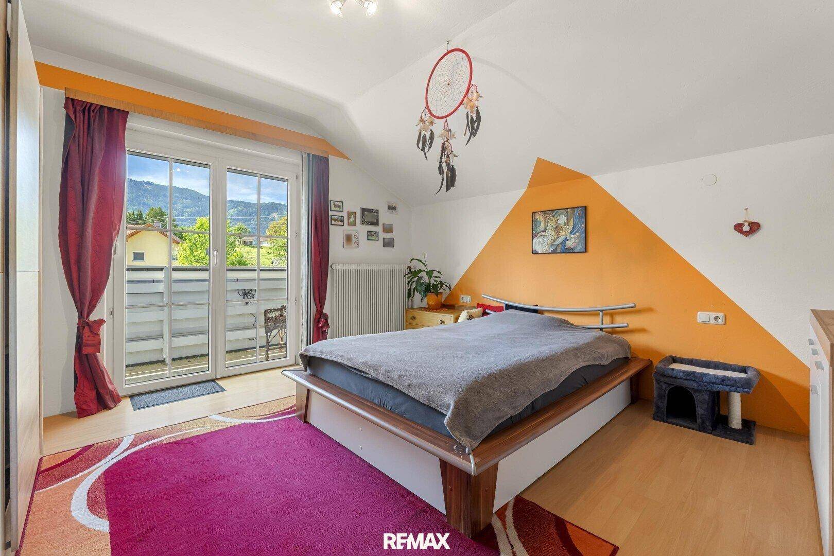 Gemütliches Schlafzimmer mit Bett, Dachschräge und Balkonzugang mit Bergblick.