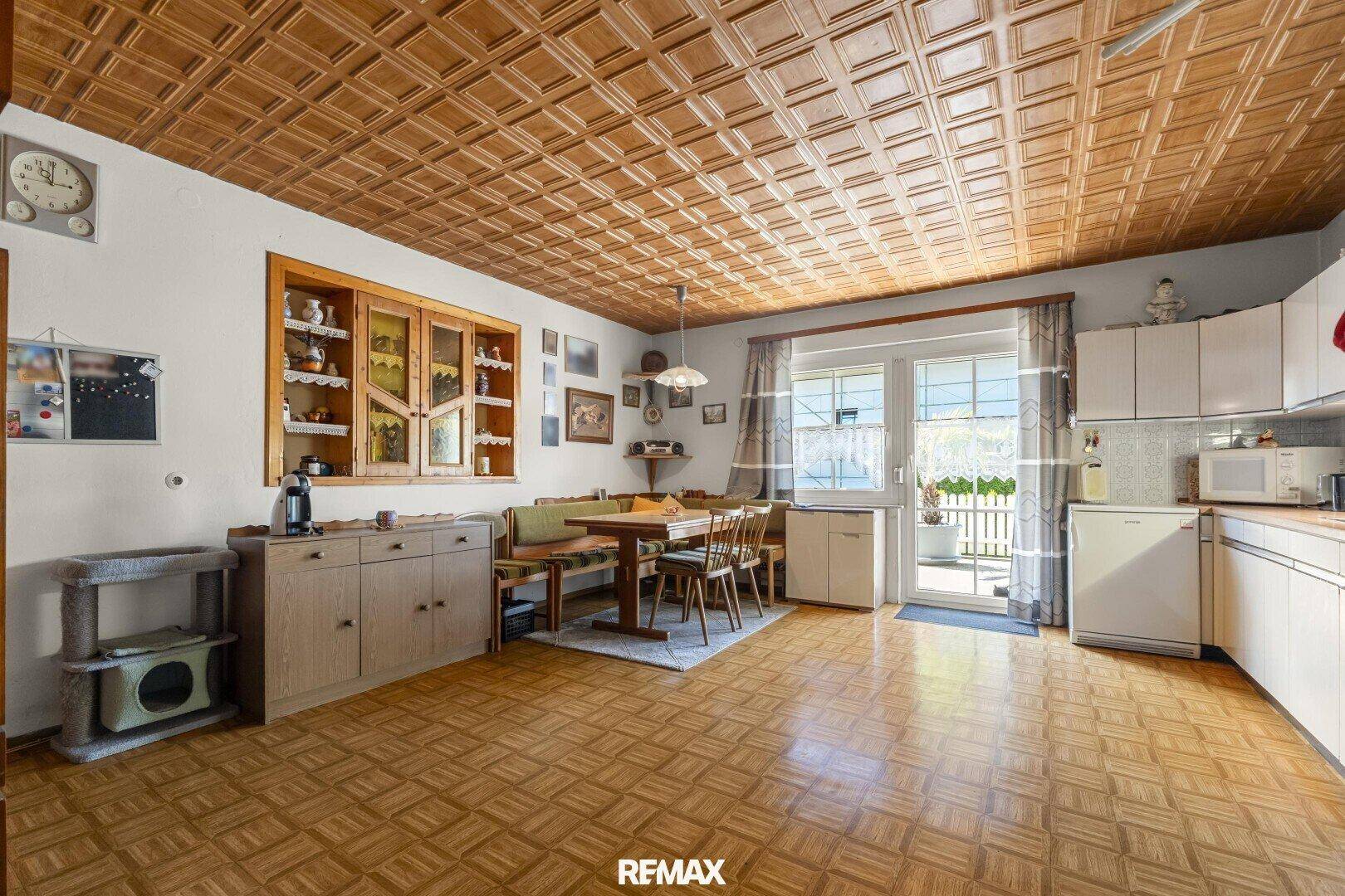Traditionelle Wohnküche mit Holzbalkendecke, Essbereich und Zugang zum Außenbereich.