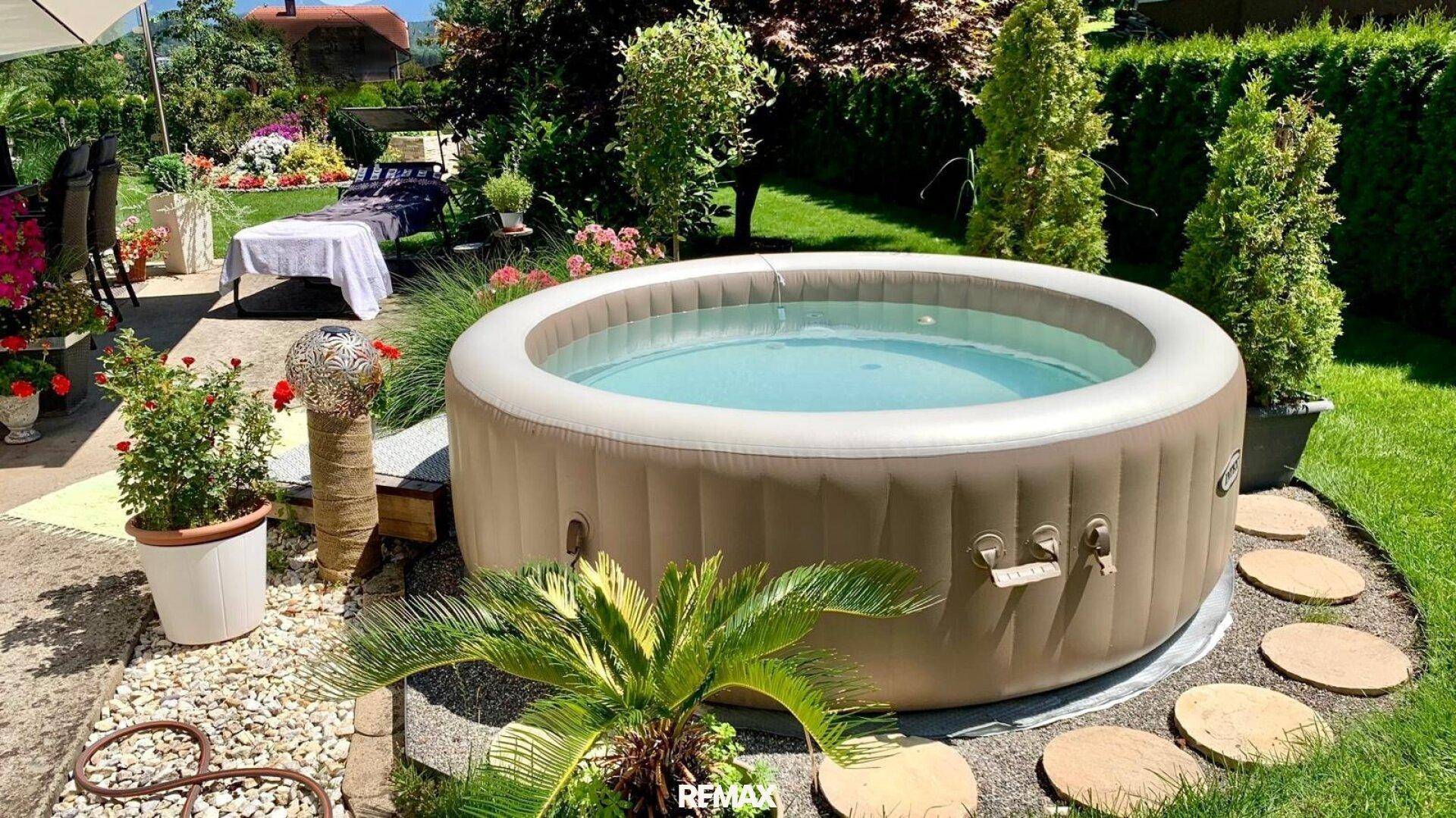 Entspannungsbereich im Garten mit aufblasbarem Whirlpool und dekorativen Pflanzen.