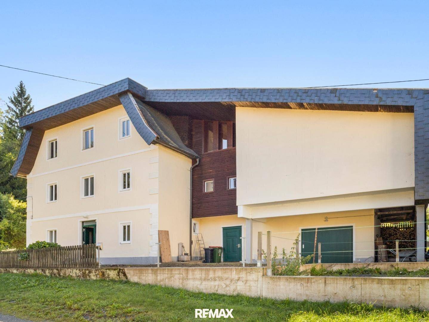 Rückansicht des Hauses mit Holzverkleidung und Satteldach, umgeben von Grünflächen.