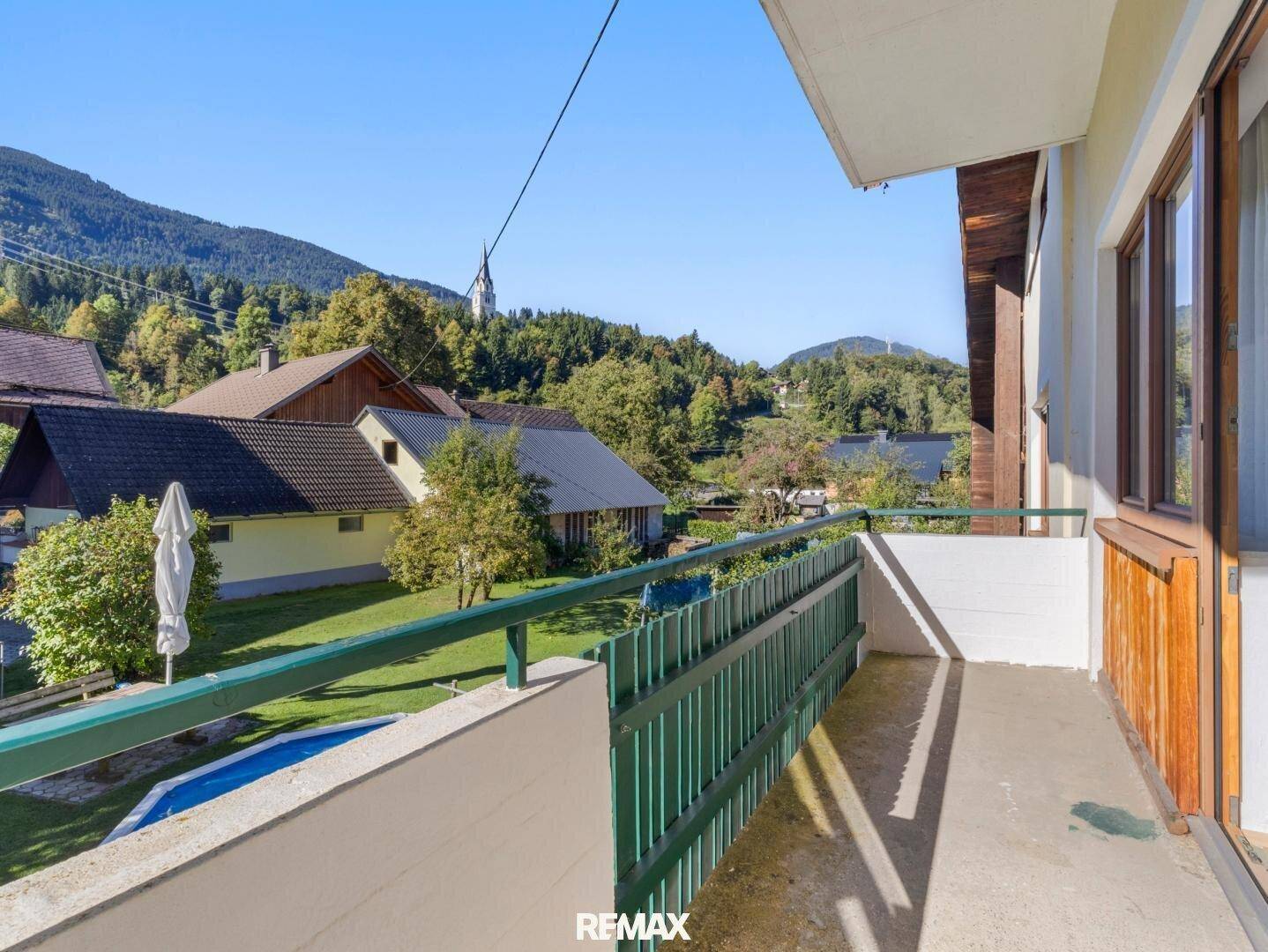 Balkon mit grüner Brüstung und Blick auf die umliegende Landschaft und einen Pool.