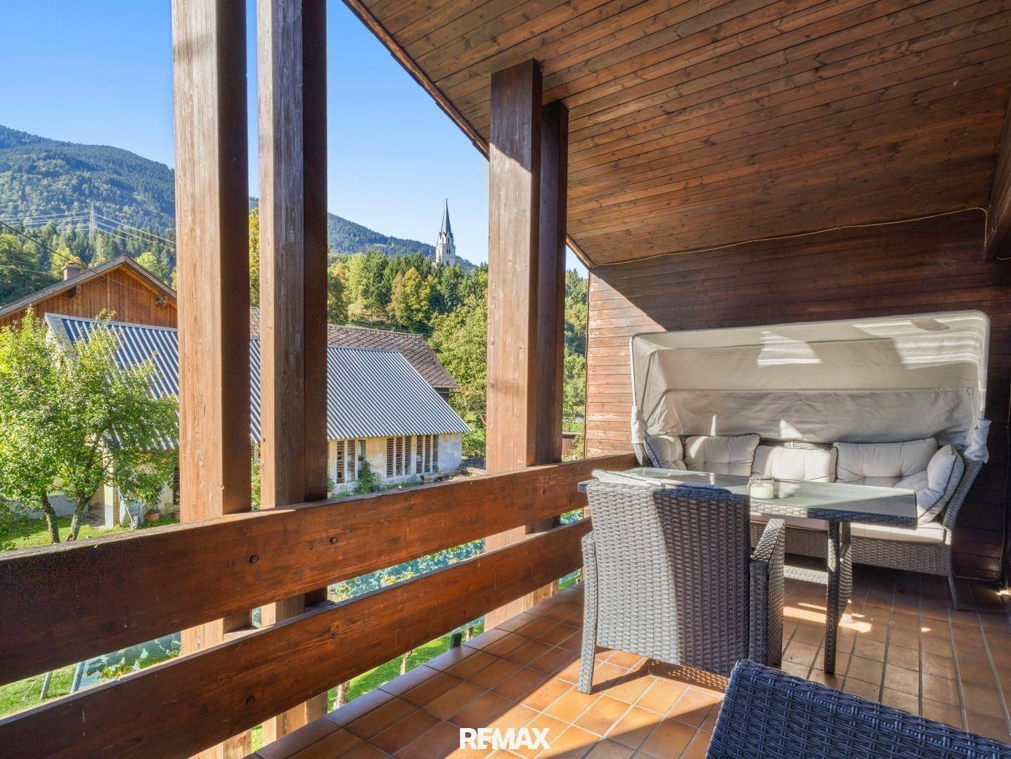 Gemütlicher Holzbalkon mit Sitzgelegenheiten und weitem Blick auf die Berge und das Tal.