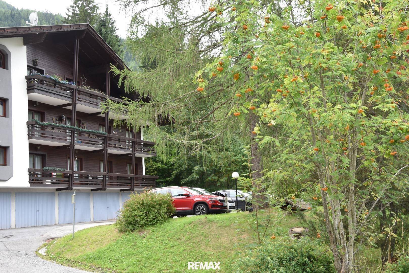 Seitenansicht des Gebäudes mit Holzfassade, Balkonen und Garagen im Untergeschoss.
