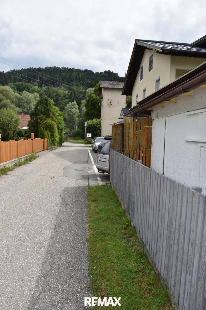 Ruhige Wohnstraße mit Blick auf die umliegende grüne Hügellandschaft und angrenzende Häuser.