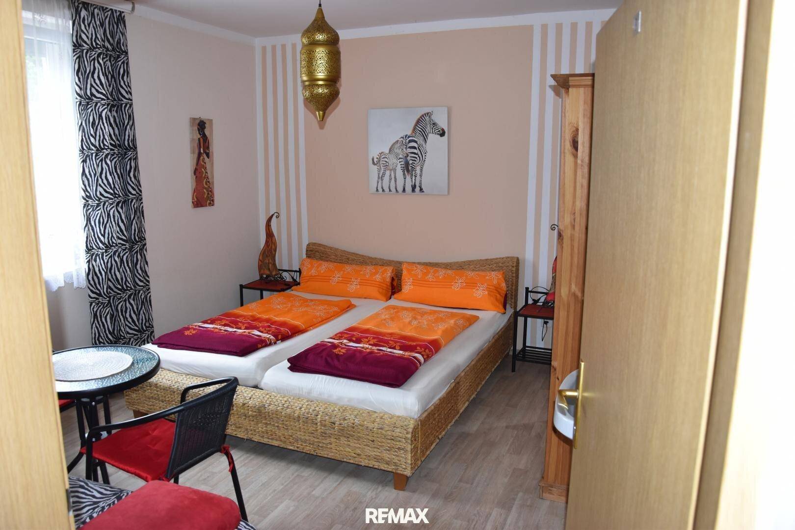 Schlafzimmer mit Doppelbett, Nachttischen und exotischer Dekoration.