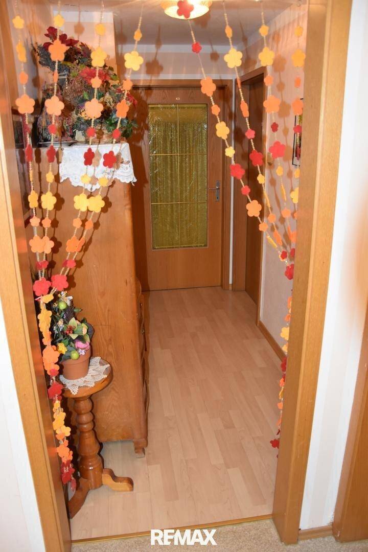 Heller Flur mit Laminatboden, einem Holzschrank und festlicher Dekoration in warmen Farben.