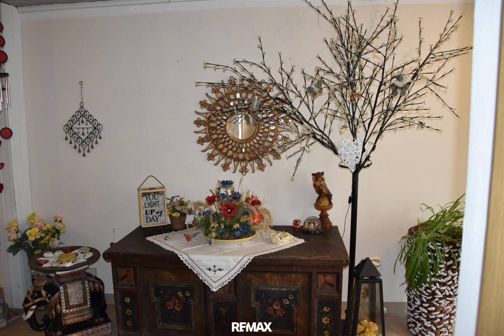 Detailansicht der traditionellen Dekoration im Flur mit Spiegel und Blumenarrangements.