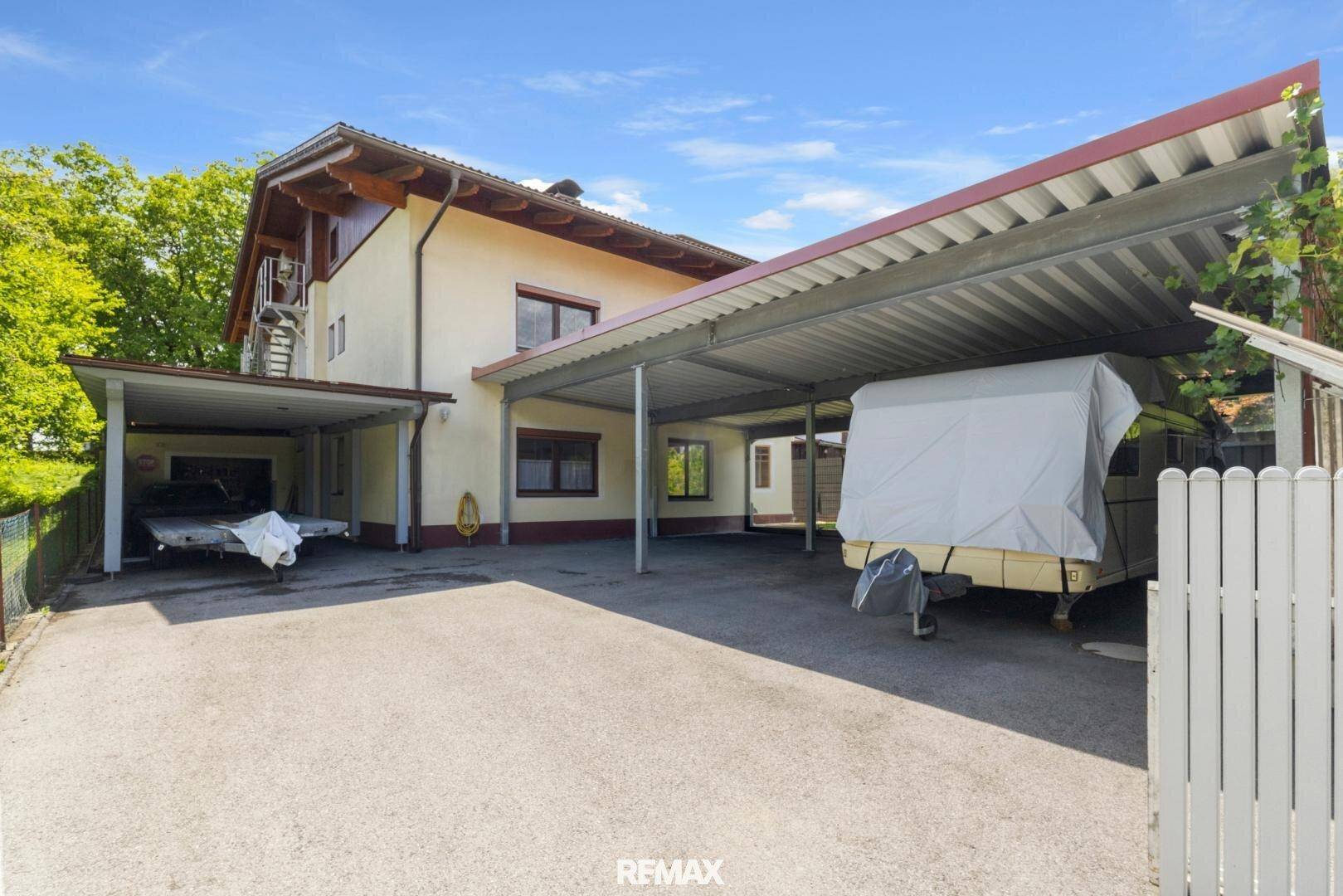 Seitenansicht des Hauses mit zwei überdachten Stellplätzen und Zufahrt.